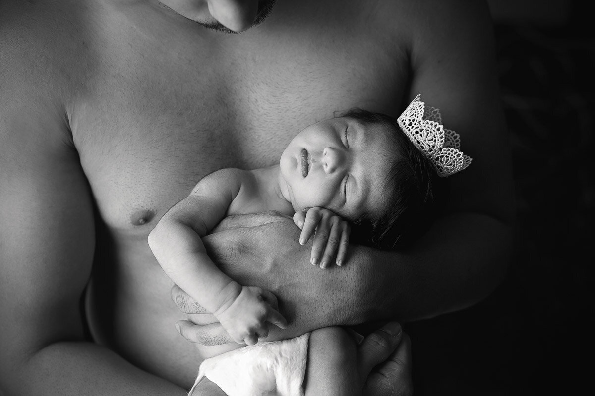 Newborn baby girl in her daddy's hands at home photo session in Calgary Alberta