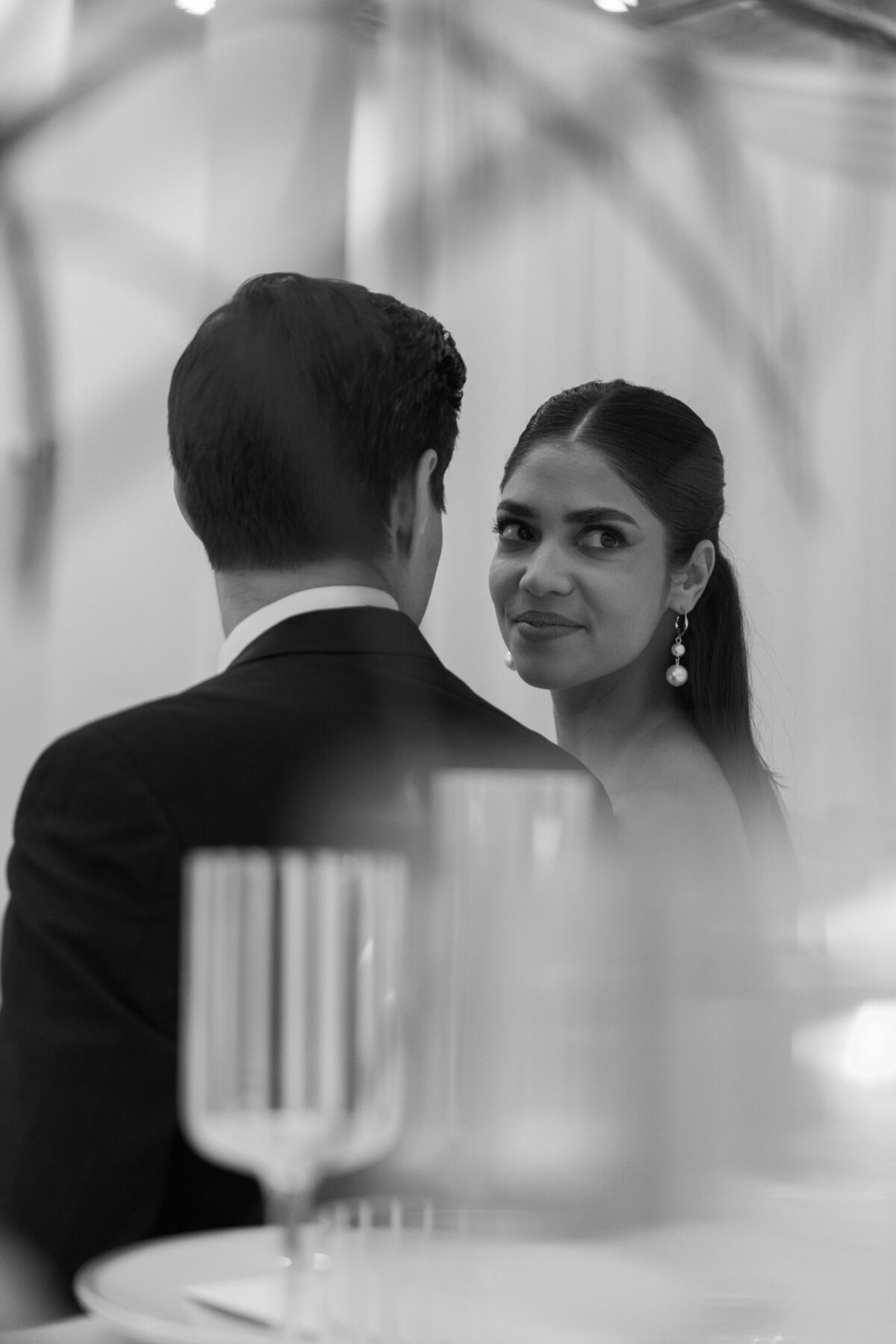 Bride giving a soft, intimate gaze over the groom’s shoulder during a modern black-and-white wedding editorial.