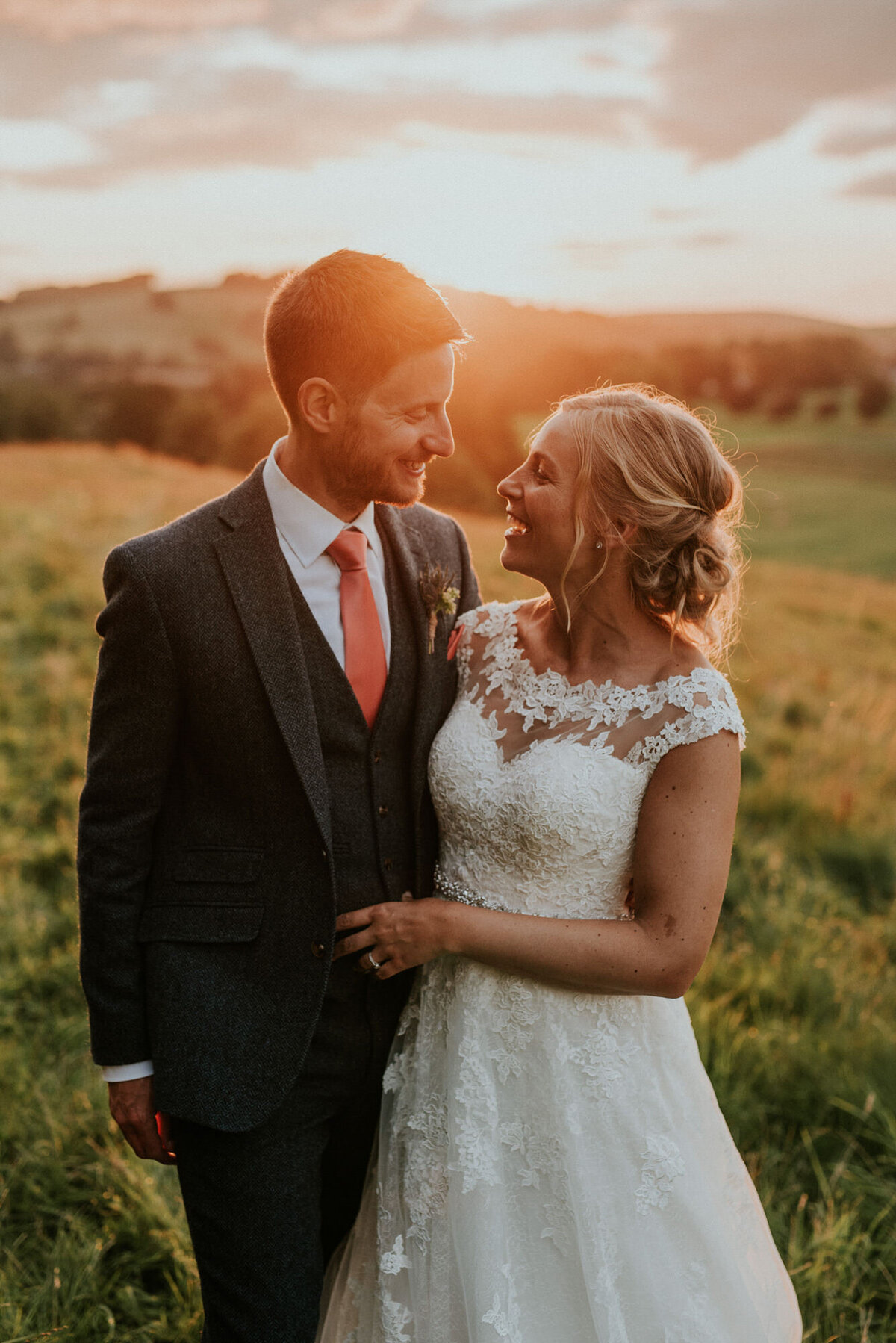 Bride and groom smiling at each other in sunlight