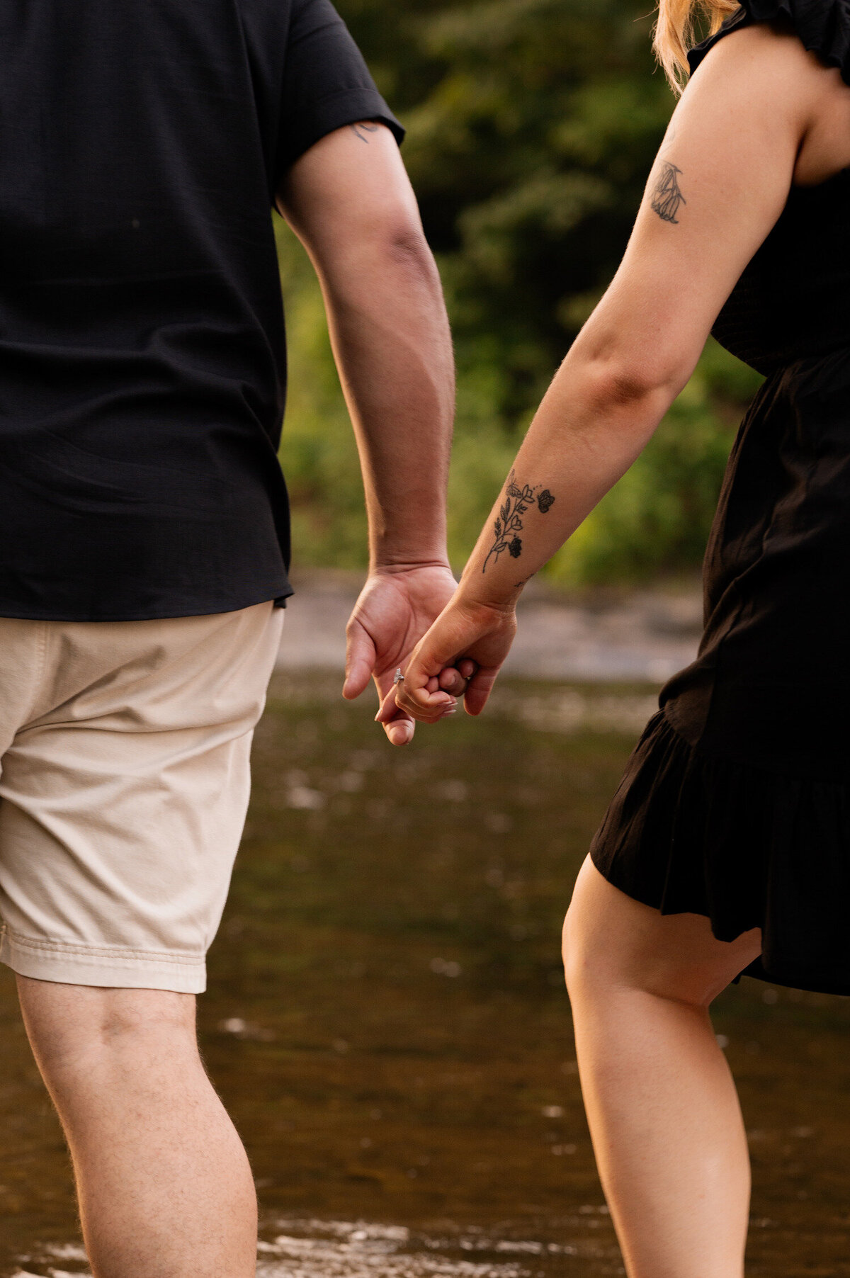 A newly engaged couple walking through a creek holding hands for engagement photos at Hudson Crossing Park in Schuylerville, NY.