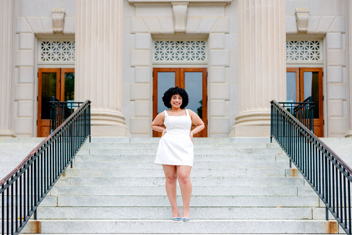 Graduate session featuring a student in a white dress with pearl accents.
