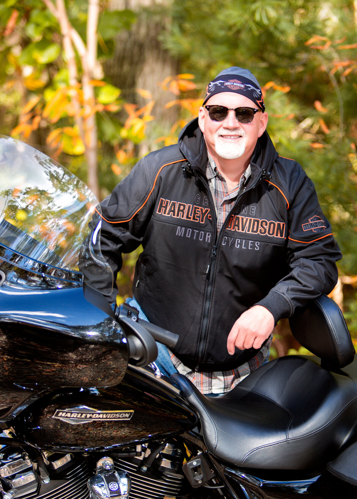 A male dating portrait client standing behind his Harley Davidson, wearing a do-rag and leather jacket