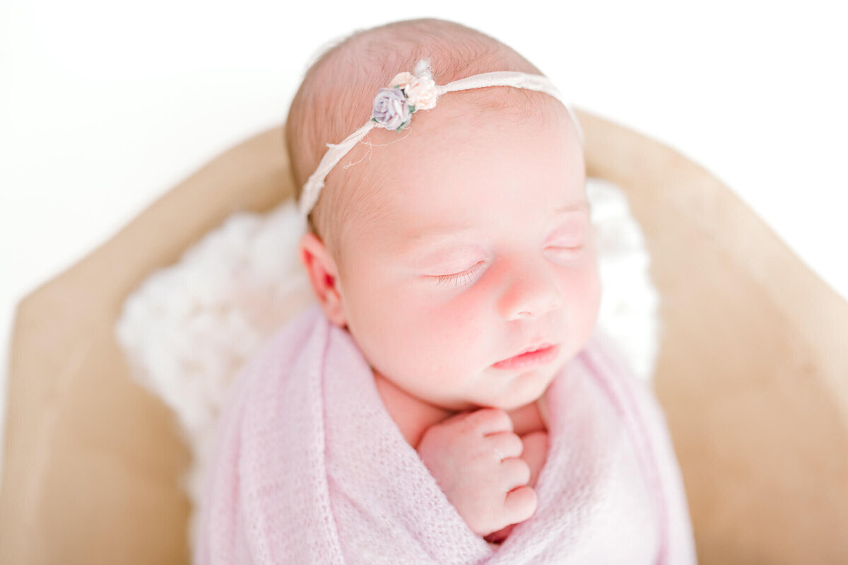 Newborn baby girl snuggled up wrapped in lilac