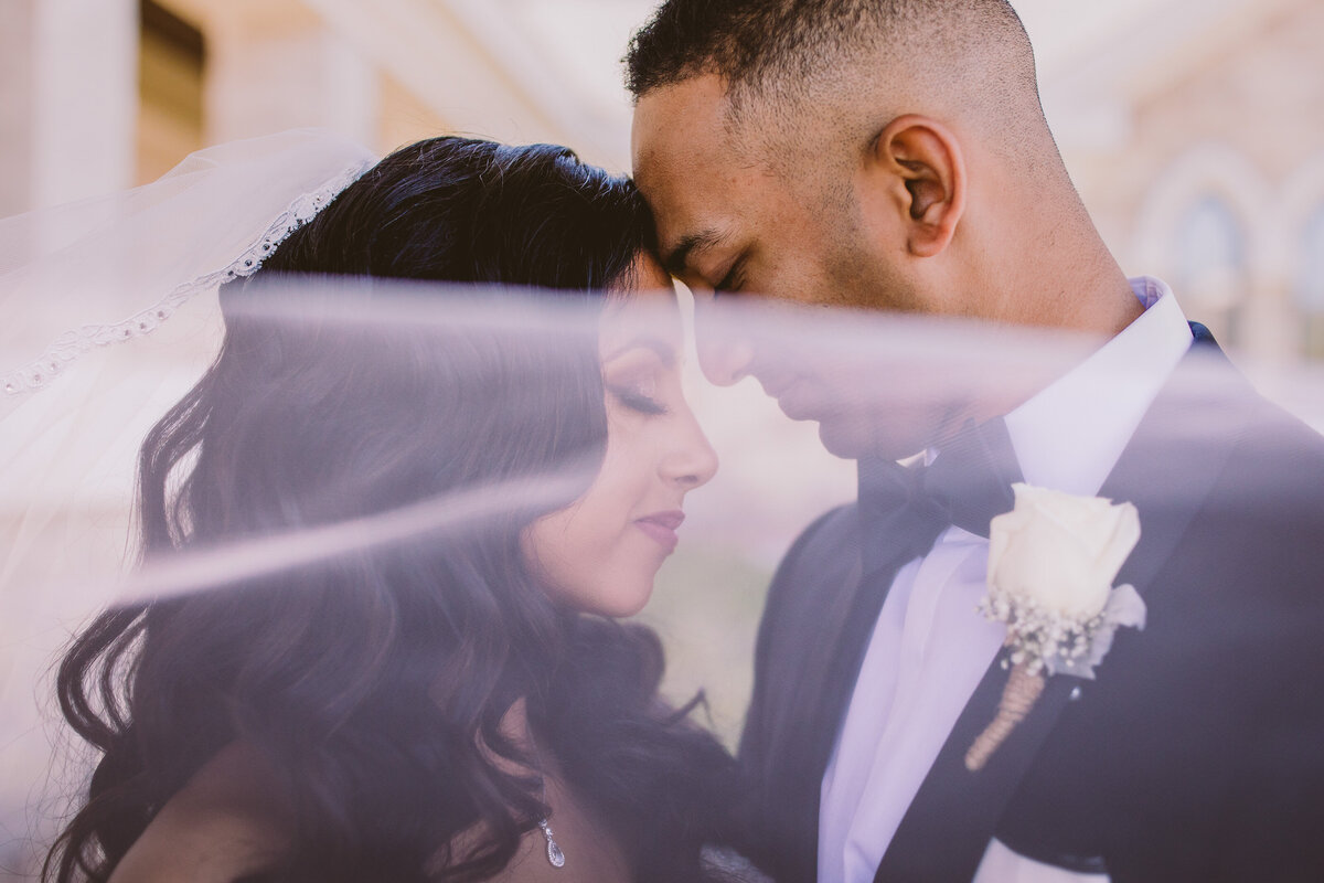 Indian christian bride touching foreheads with the veil covering their faces
