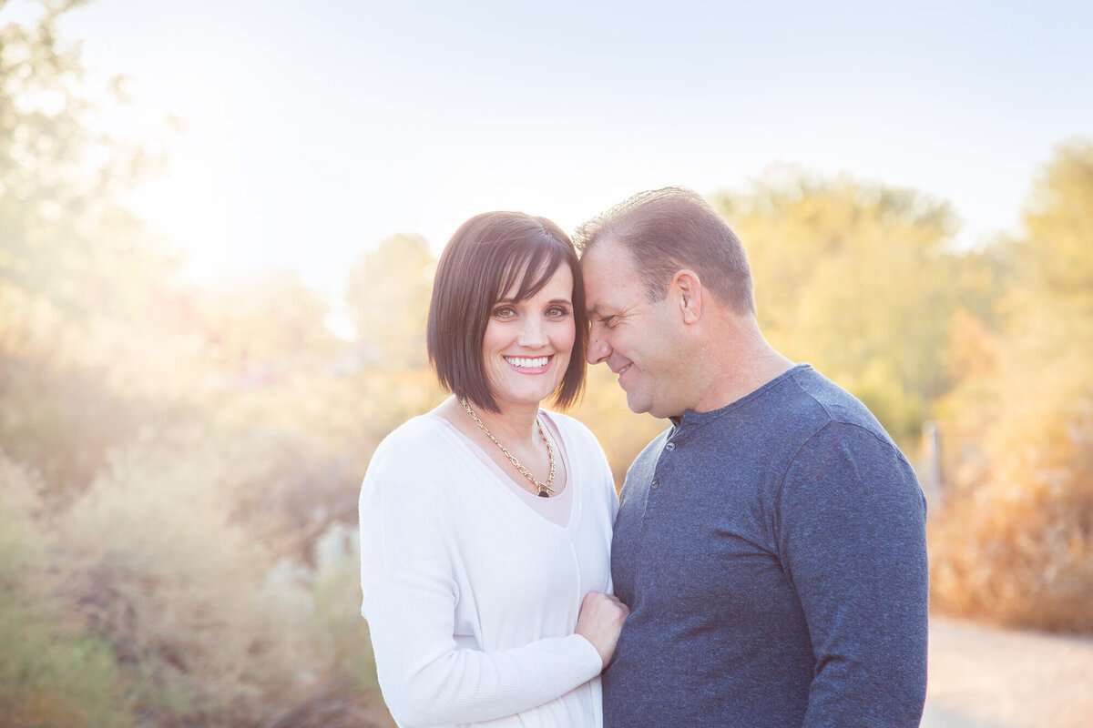 Couple in a desert park with heads together, husband looking at his wife