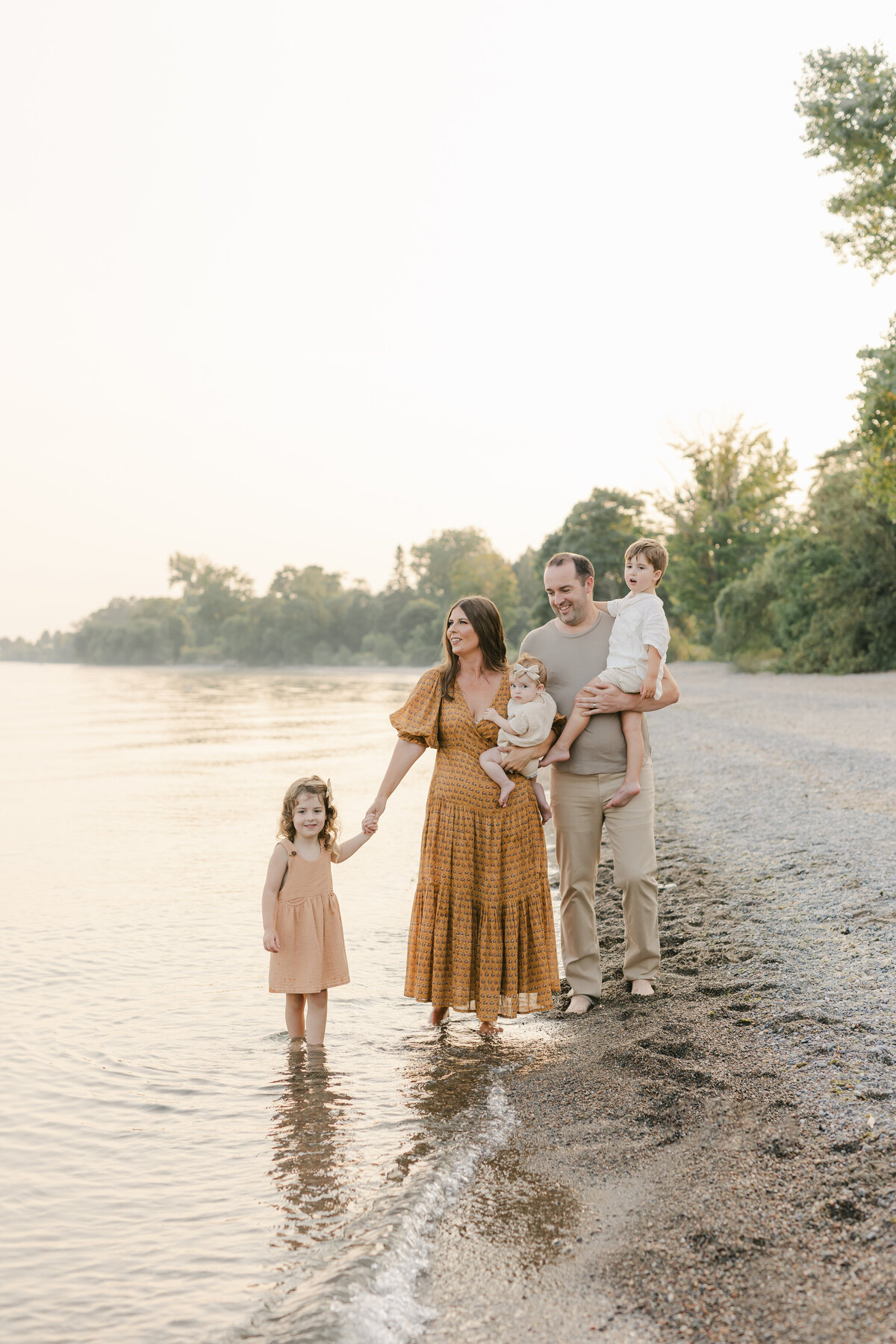 A family of 5 holding hands and walking at the beach in Toronto
