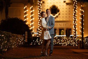 Romantic couple embracing in historic St Augustine district at night with twinkling lights, captured by professional elopement photographers