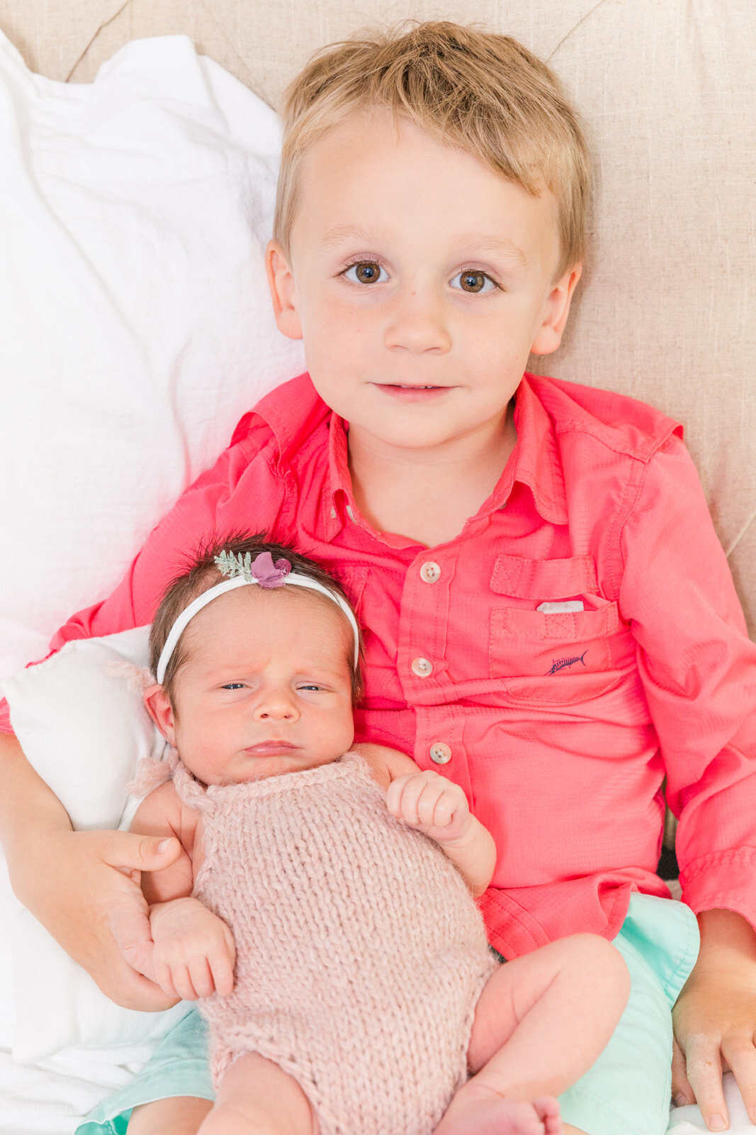 todder sibling sitting and holding newborn baby