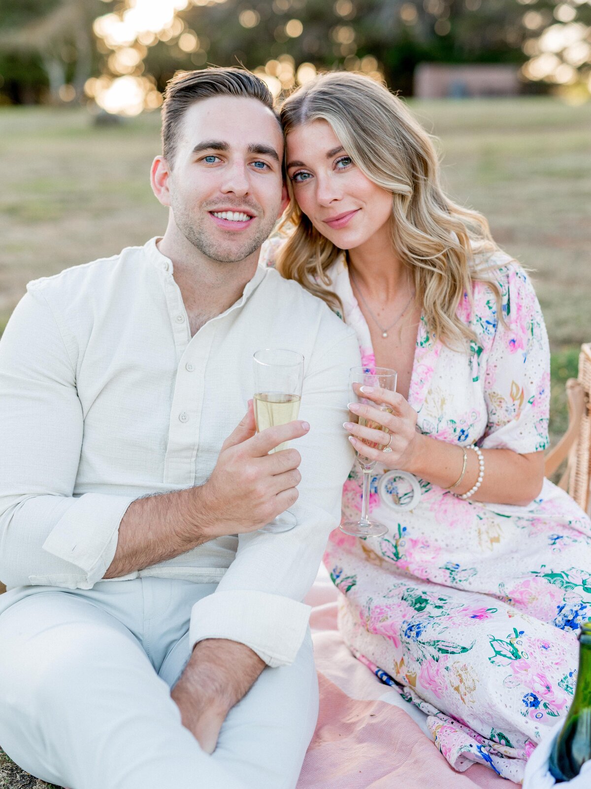 Engaged couple toasting with champagne during a picnic