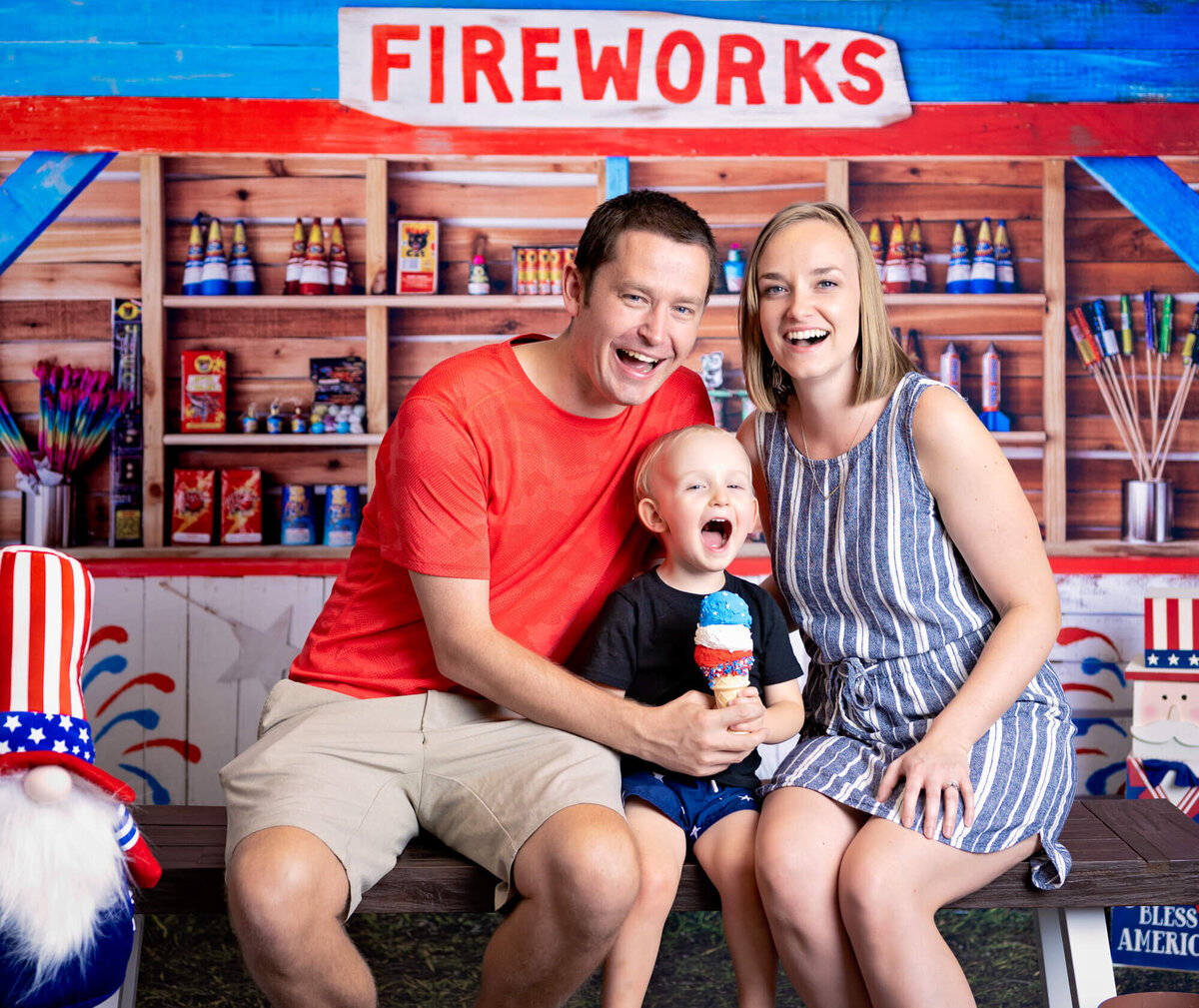 Parents pose with son in front of fireworks stand in Prescott family photos