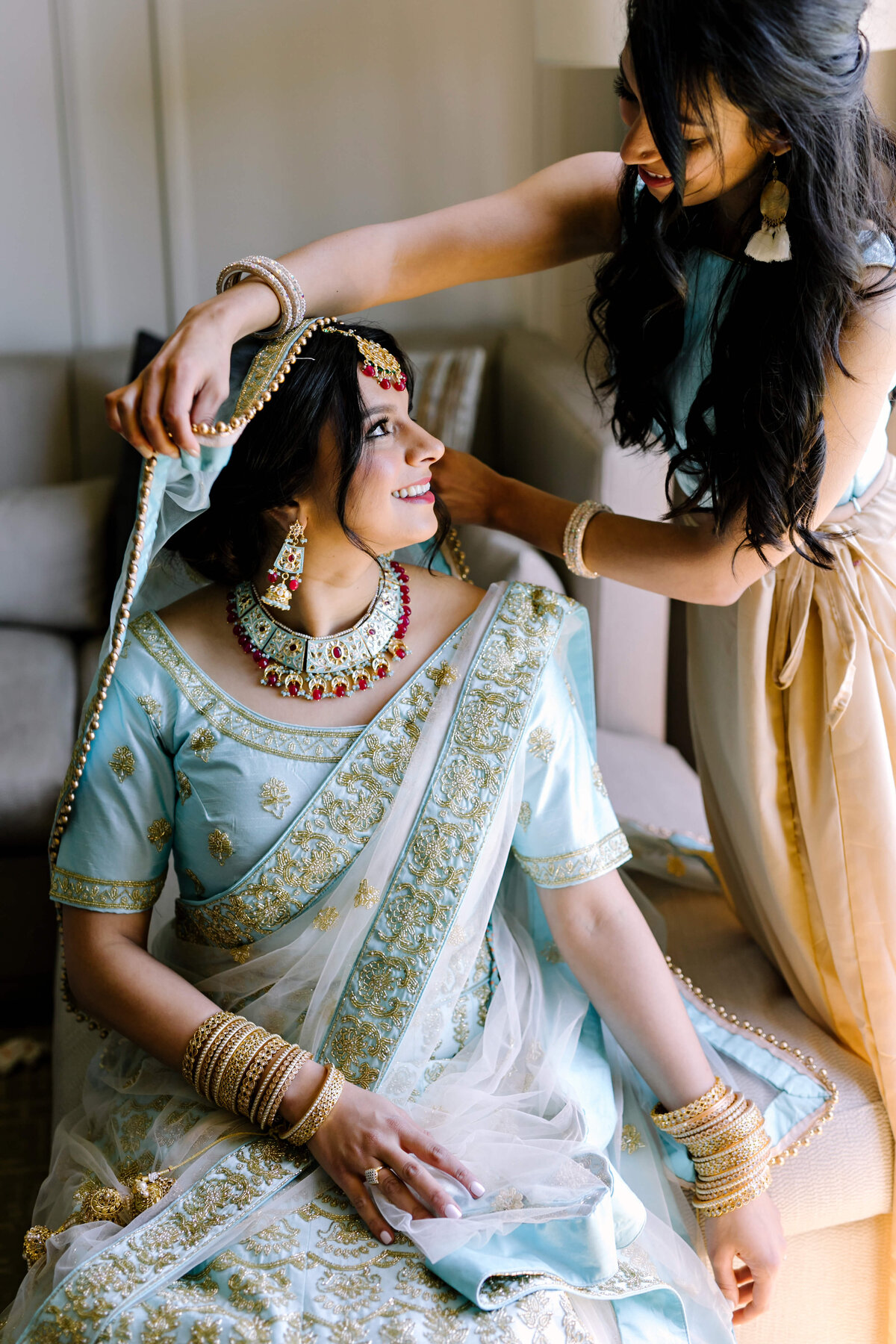 bride getting dressed in her traditional lehenga