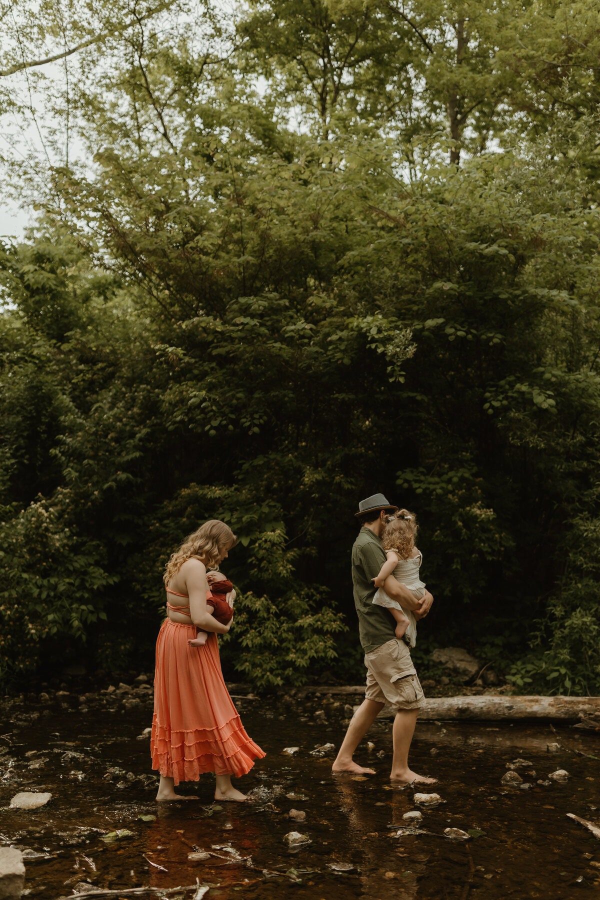 family walking together in creek during a family photoshoot in indiana