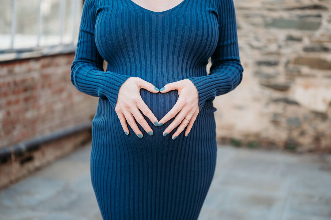 Pregnant mom holding her belly with her hands shaped like a heart