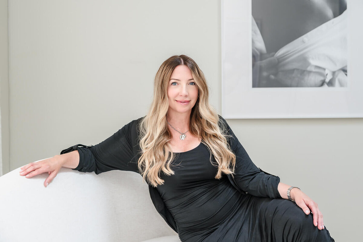 smiling elegant spa owner on white couch for social media content
