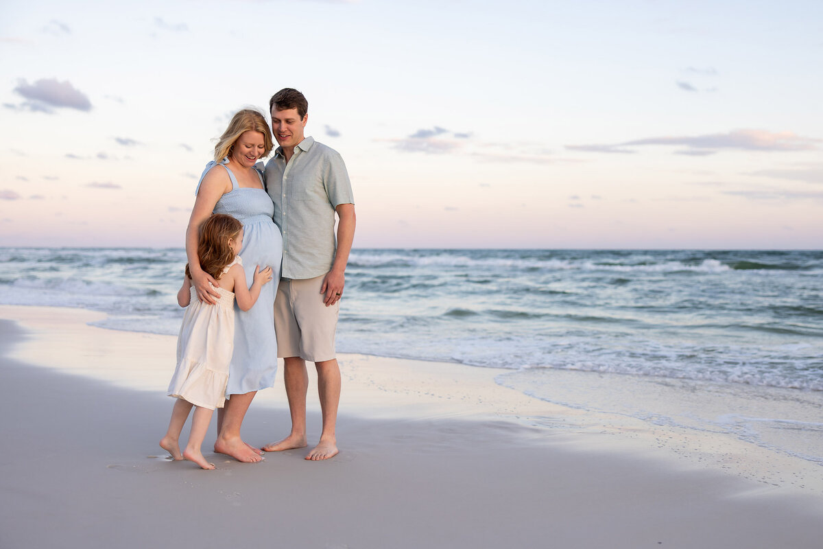 family of three on the beach in seacrest with mom pregnant with next daughter.