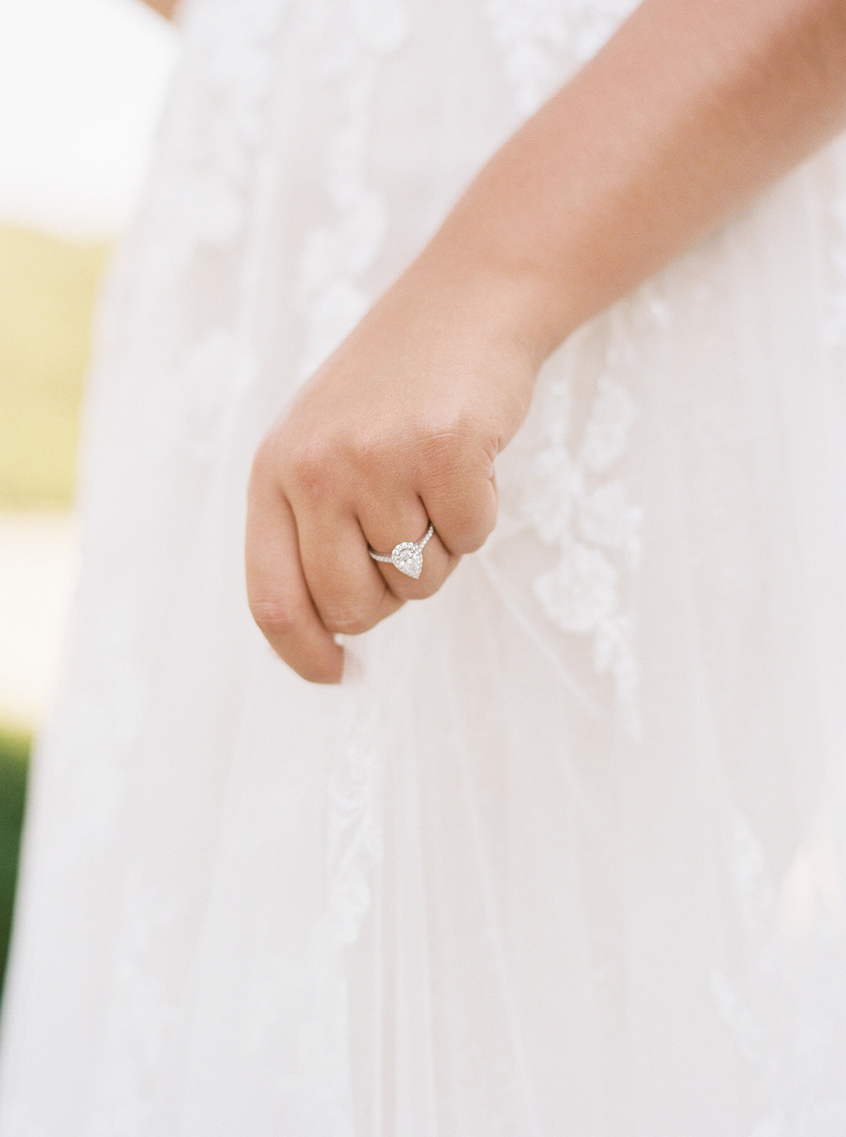close up of bride's hand with an ring on holding her wedding dress