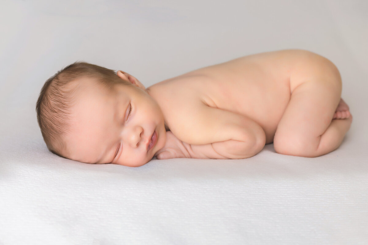 Newborn Photographer,  a baby lays on bedsheets