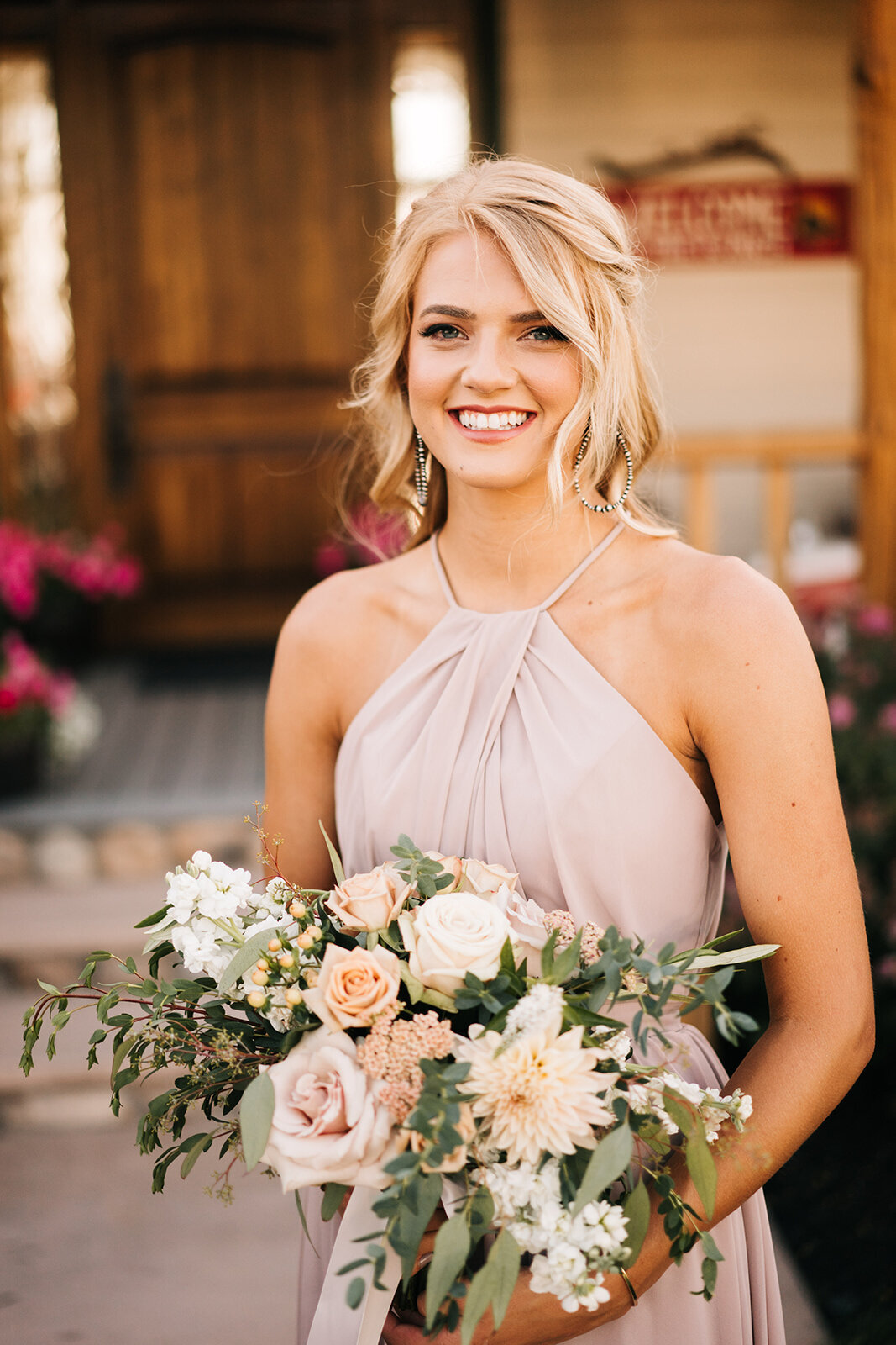 Bridesmaid in pale mauve dress holding a bouquet of roses, dahlias and stock with eucalyptus