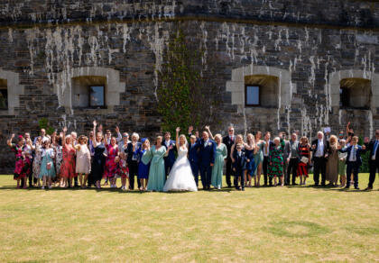 A large group of wedding guests congregating for a wedding photo.