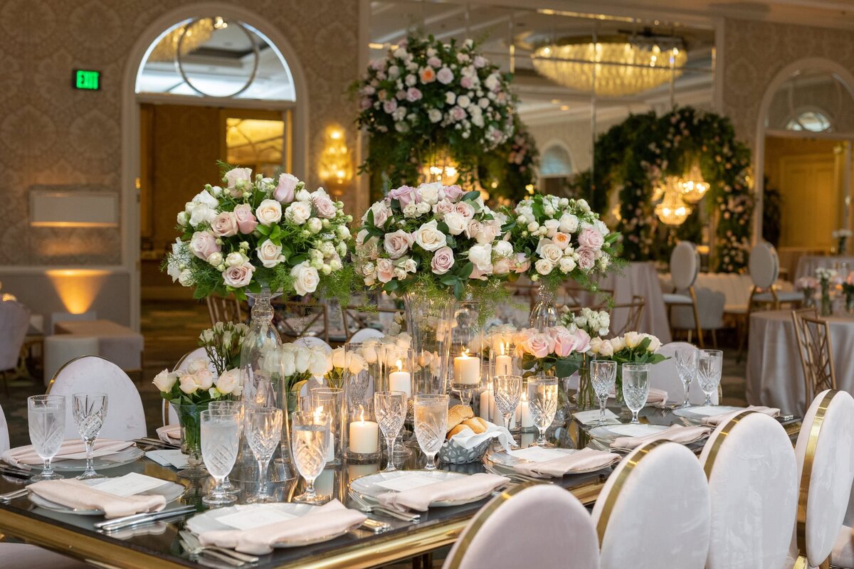 A wedding reception table with large flower arrangements in the middle