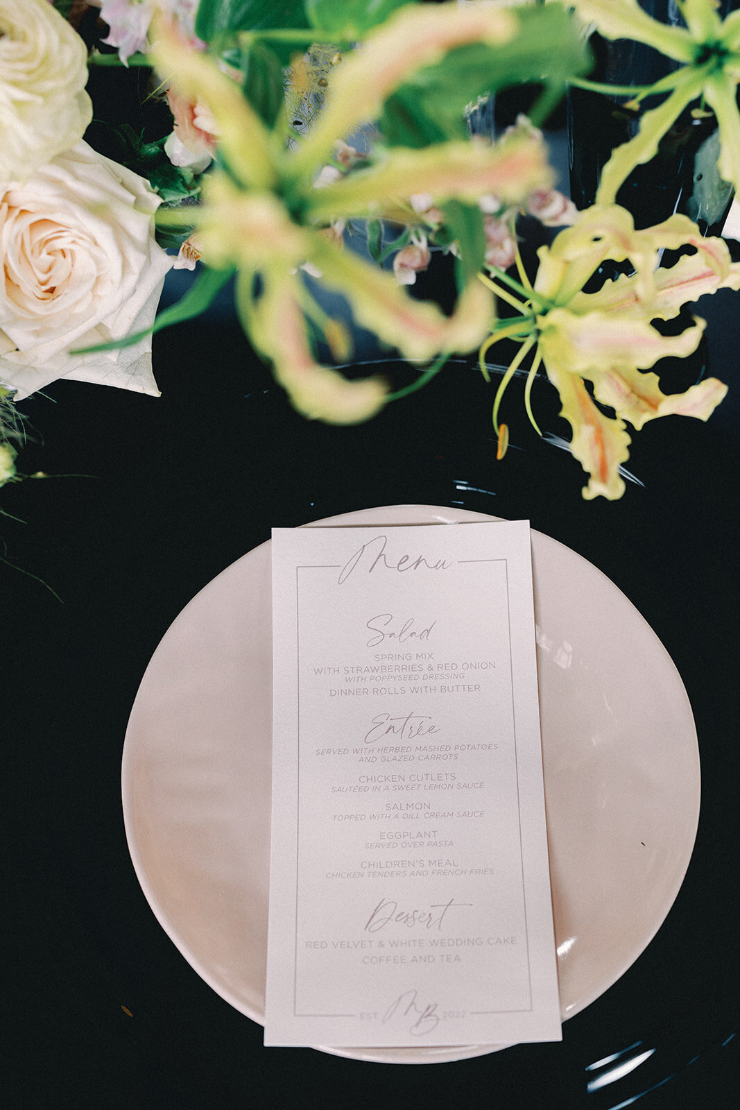Table setting with a menu on a plate on a black table