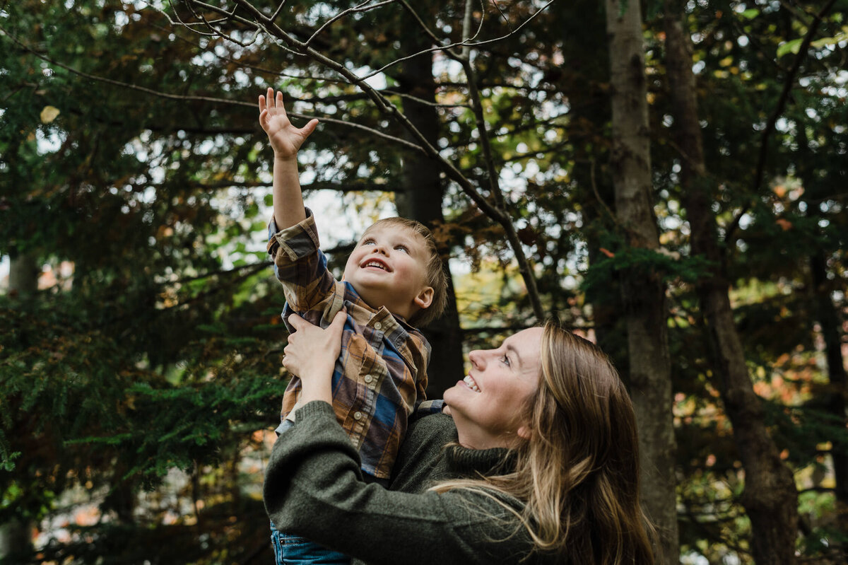 Woman holding child reaching for leaf.