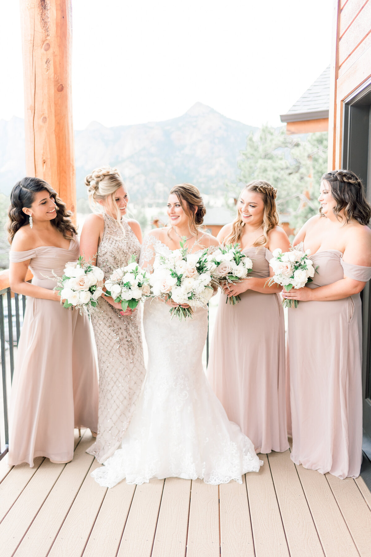 bride and her bridesmaids looking at eachother and smiling at the black canyon inn wedding venue in estes park