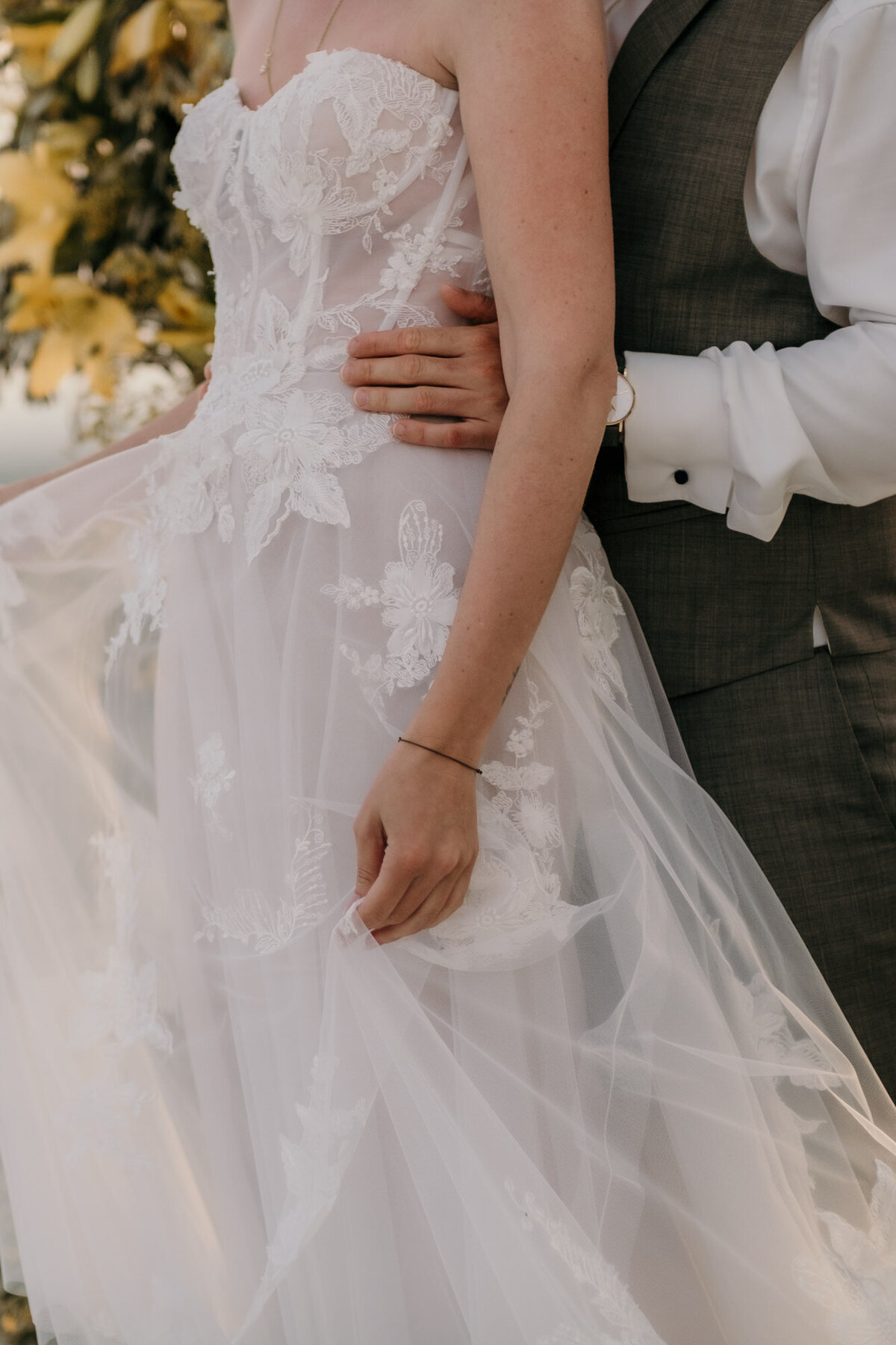 Dieser Ausschnitt zeigt die Braut mit dem Rücken an ihren Mann gelehnt, ihr Kleid haltend.
