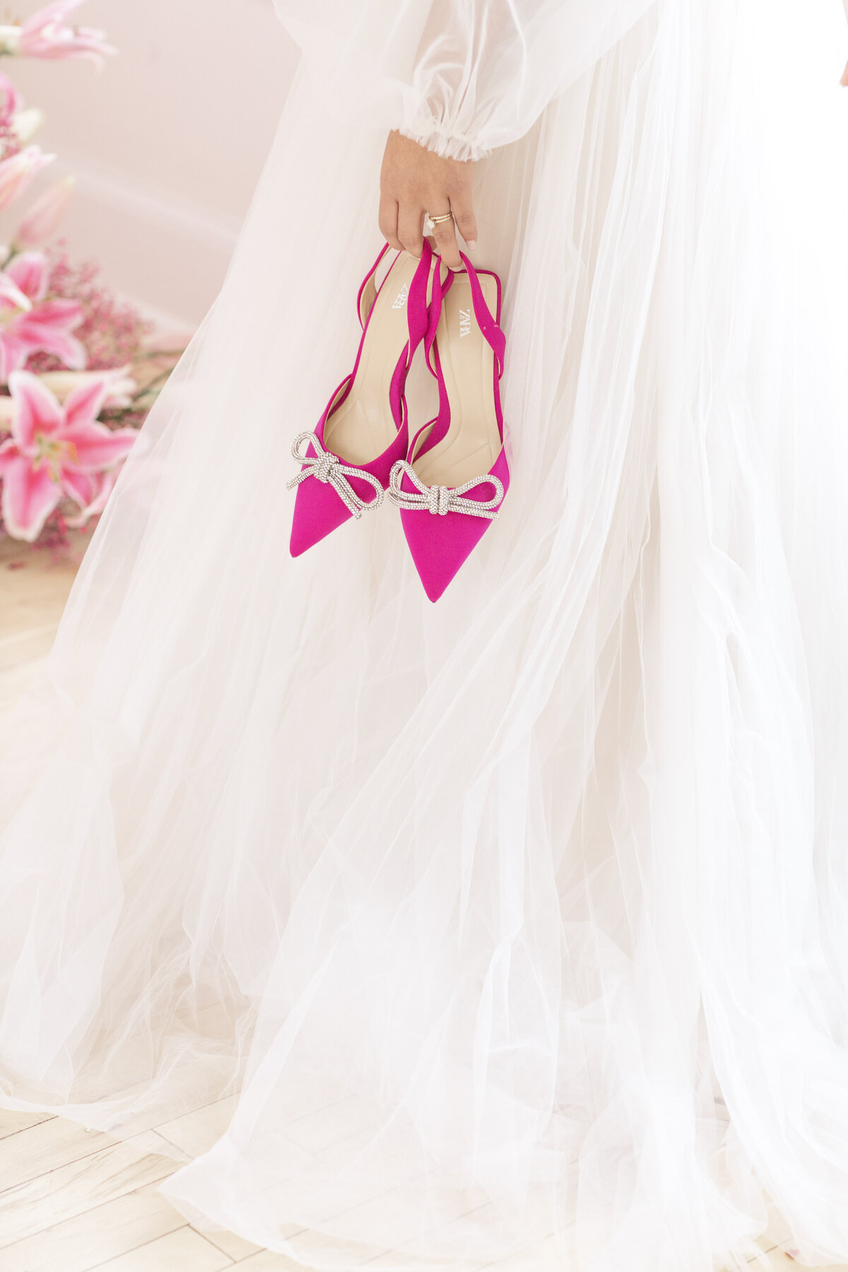 bride holding bright pink shoes