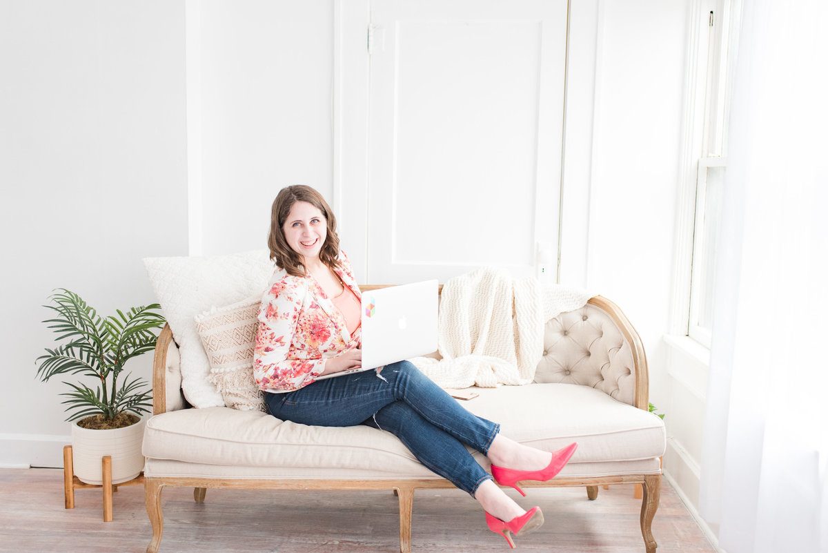 Woman sitting on a cream couch holding a laptop