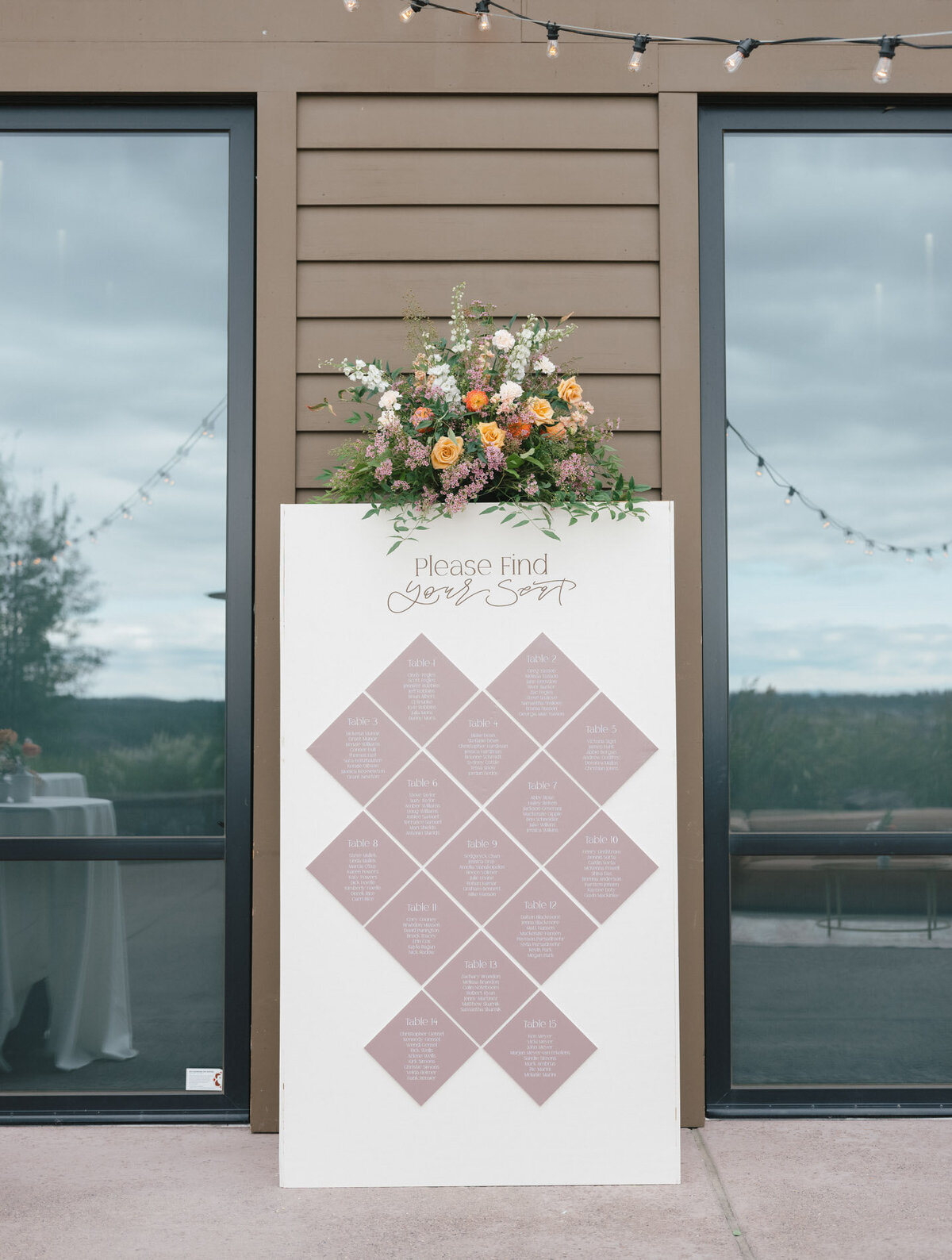 custom seating chart calligraphy wall in front of wedding venue entrance with florals on top representing full service design and calligraphy by Life in Letters.