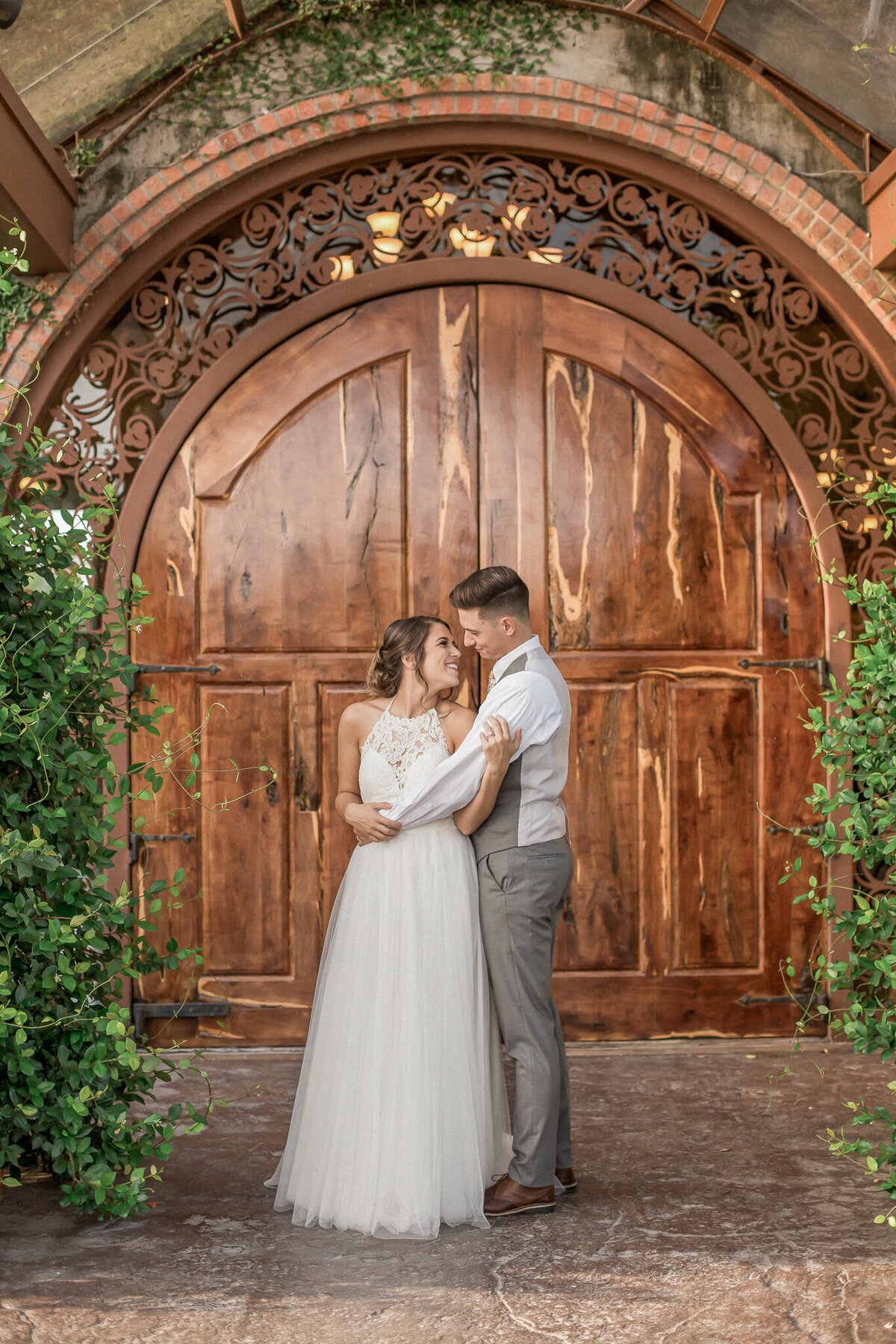 The bride and groom pose in front of  a grand set of wooden doors outside of Olde Dobbin station