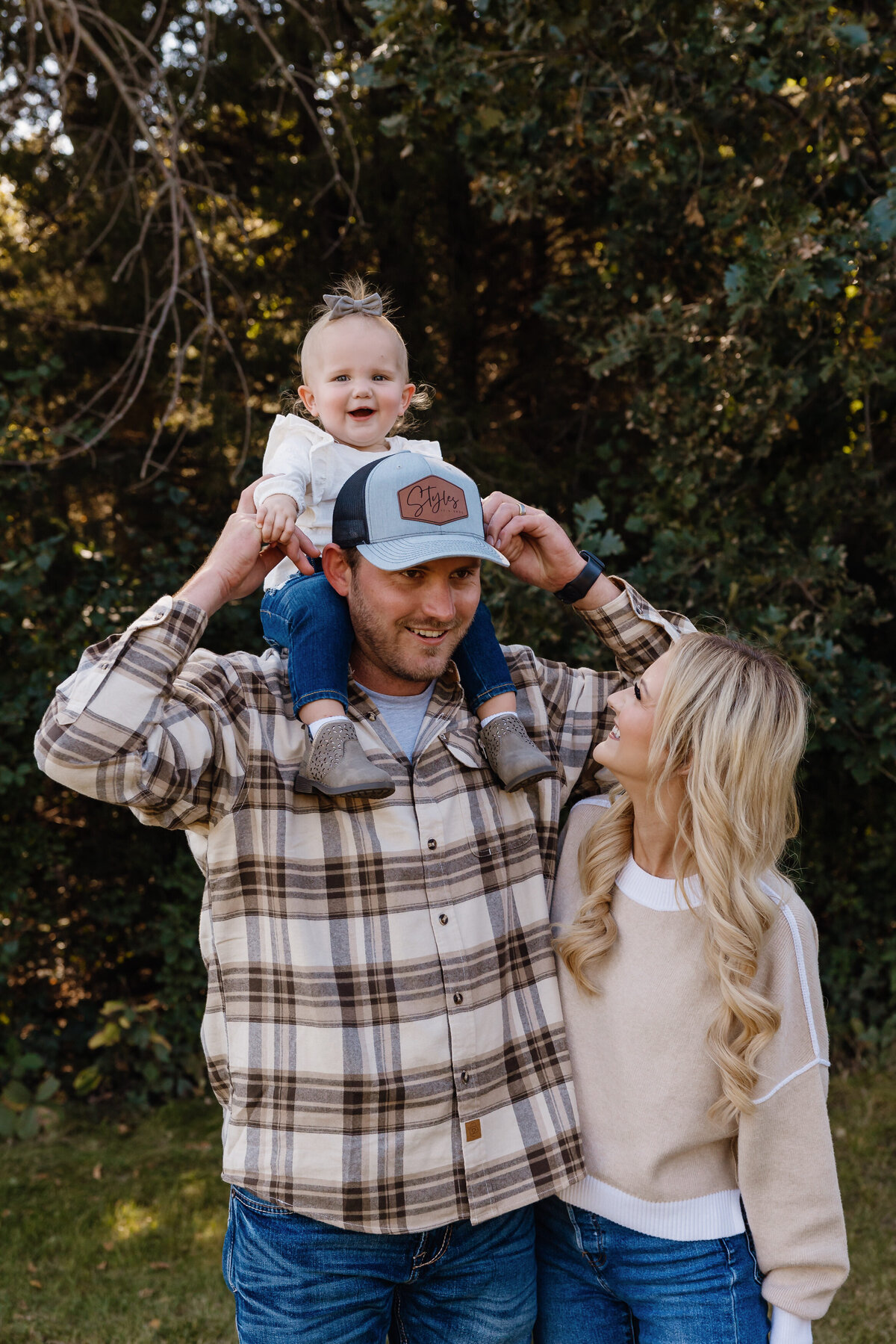Two parents standing together while one has a small child on their shoulders
