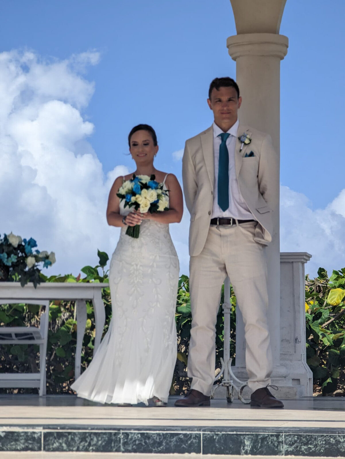 Bride and groom standing in front of the guests while bride holding floral bouquet