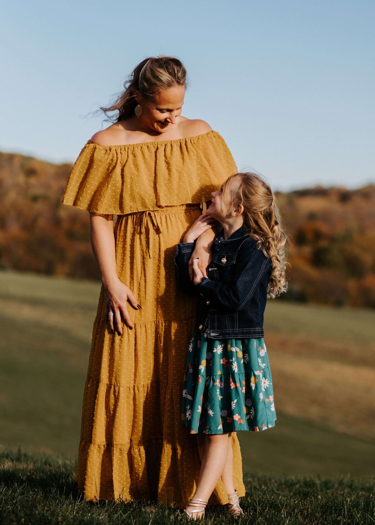 A mother and daughter in yellow dresses stand in a field. Based in Pittsburgh, the family photographer captures this beautiful moment.