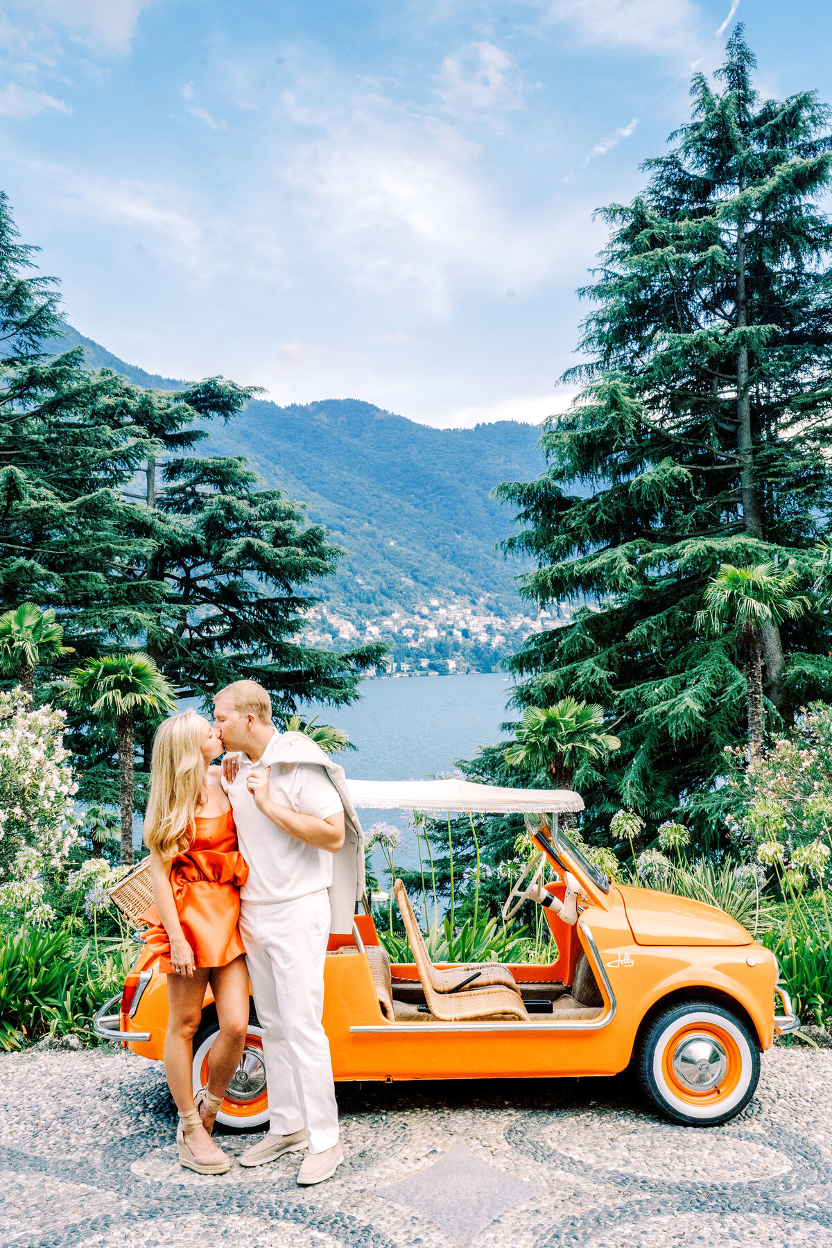 Film photograph of couple with vintage orange car at their engagement session at Passalacqua on Lake Como Italy