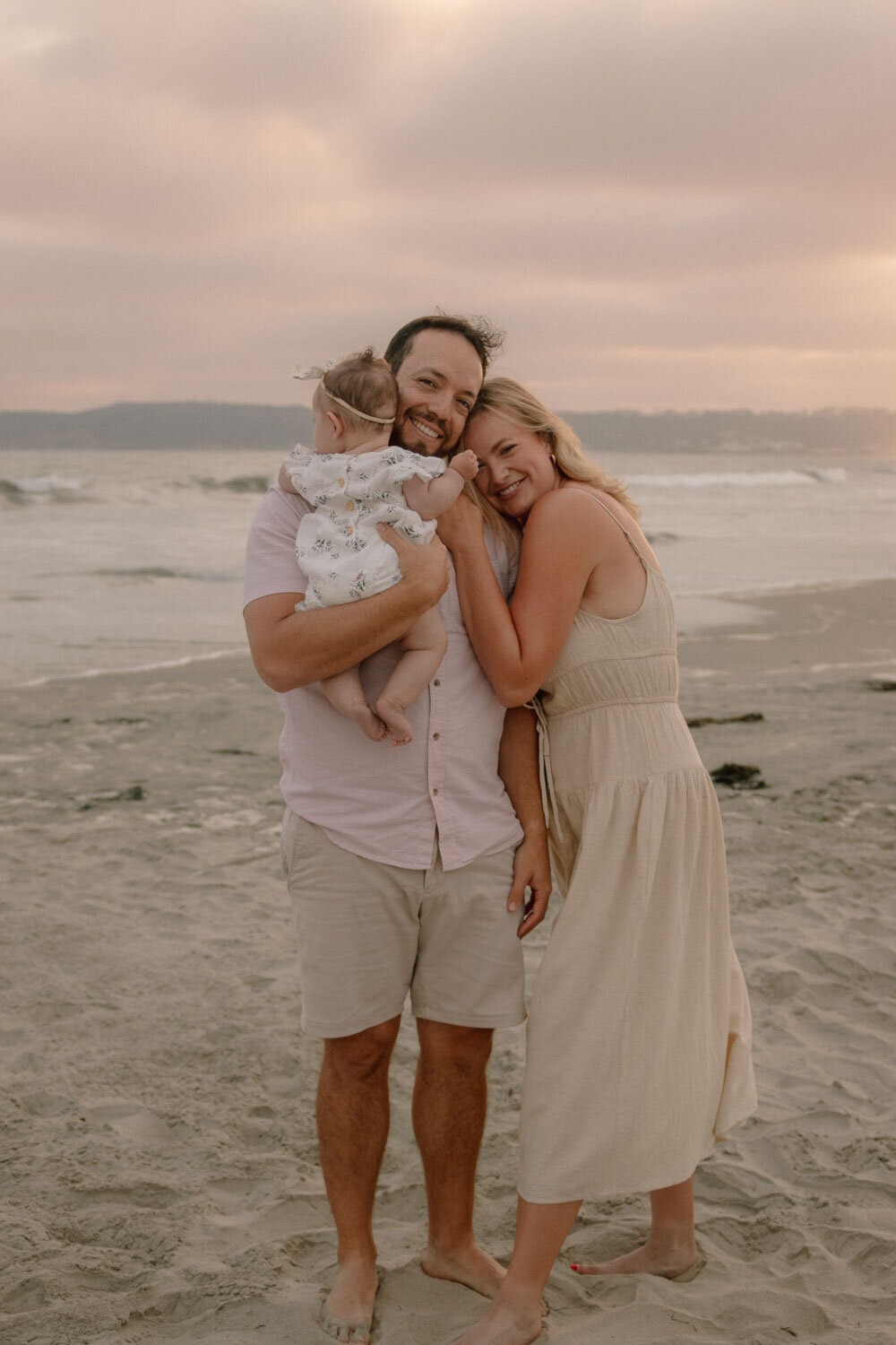 Family posing on the beach, parents hugging each other