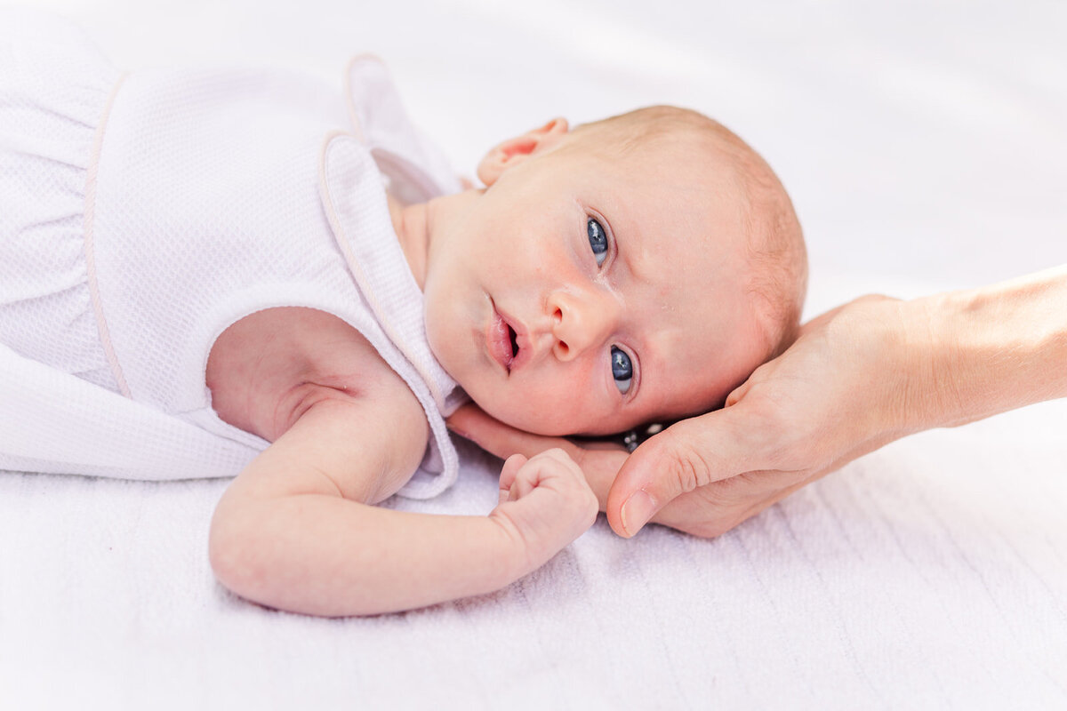 newborn baby head resting on parent hand
