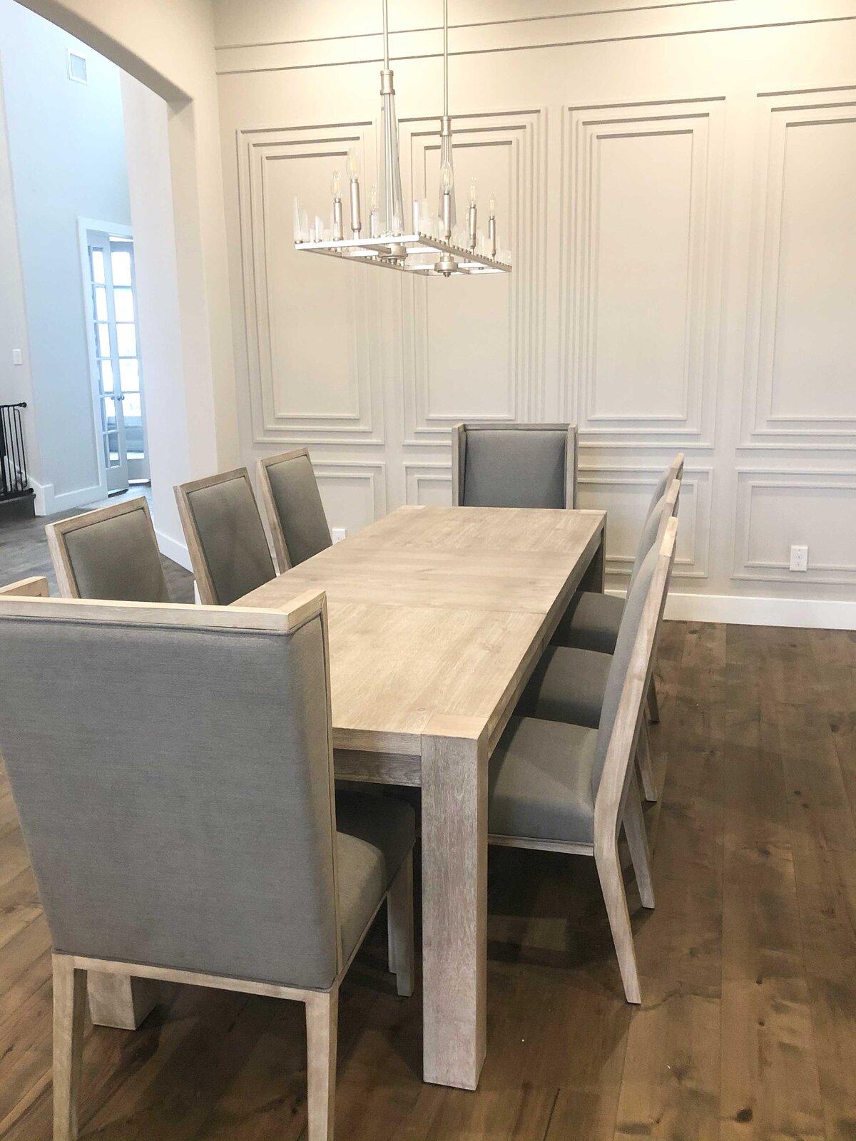 Renovation and interior design services featuring a wood dining table with sophisticated decorations. The wall is designed with elegant materials to enhance the space's luxurious feel.