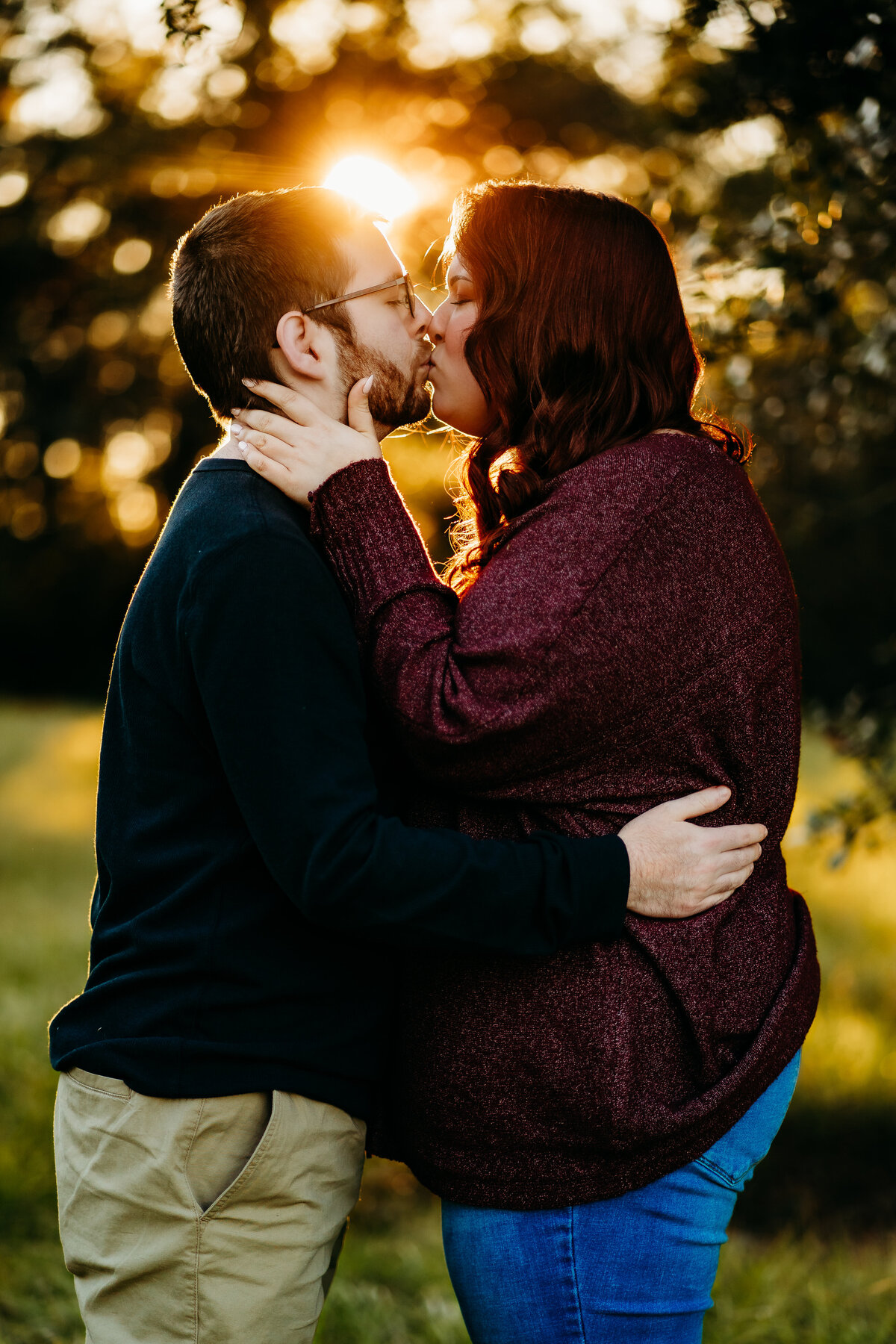 romantic photo of kissing candid engagement photo of couple cuddling in field at sunset in Lafayette, la
