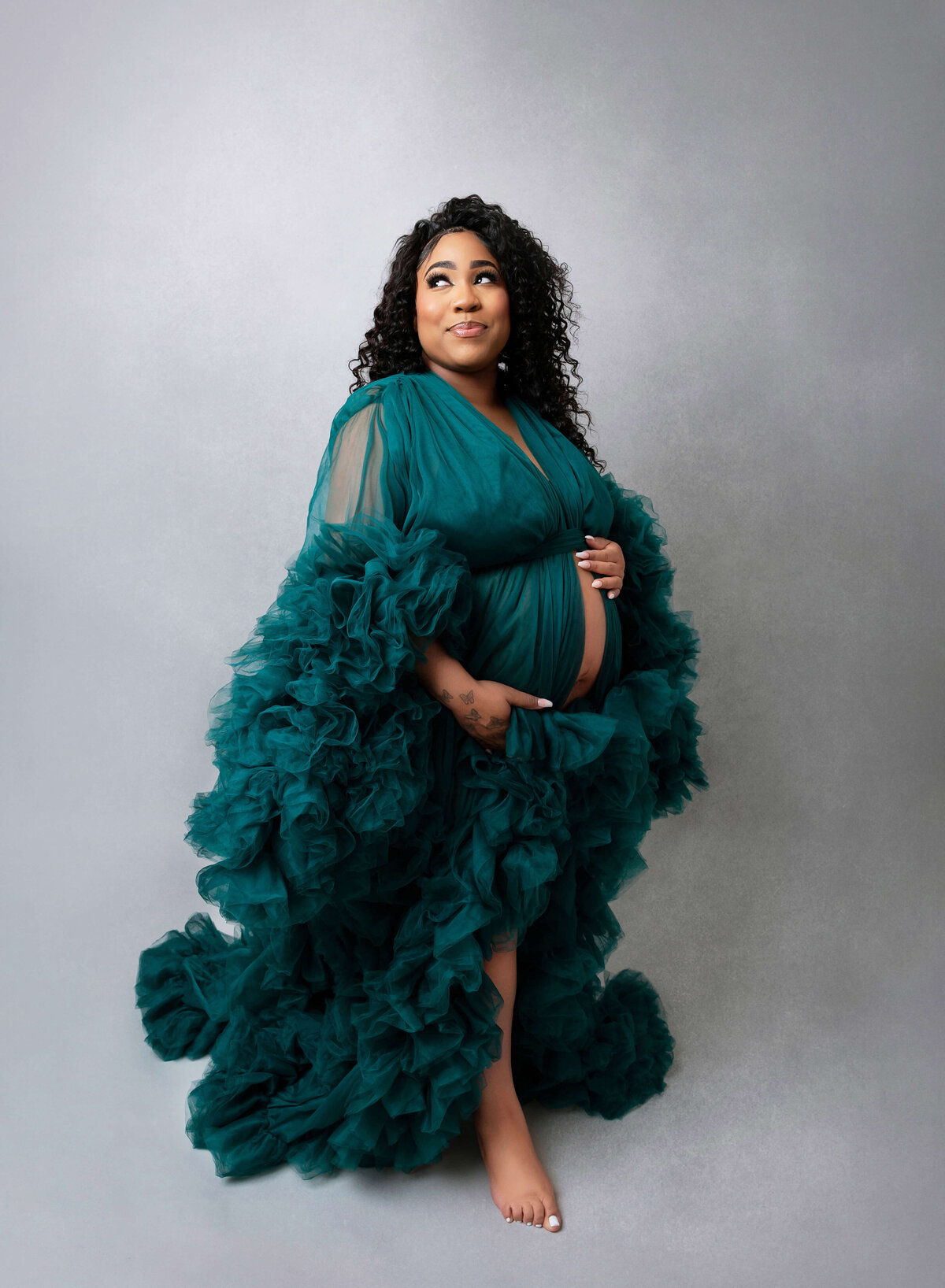Expectant mother in a flowing green gown, captured during a stunning maternity photoshoot in Brooklyn, showcasing the beauty and grace of pregnancy.