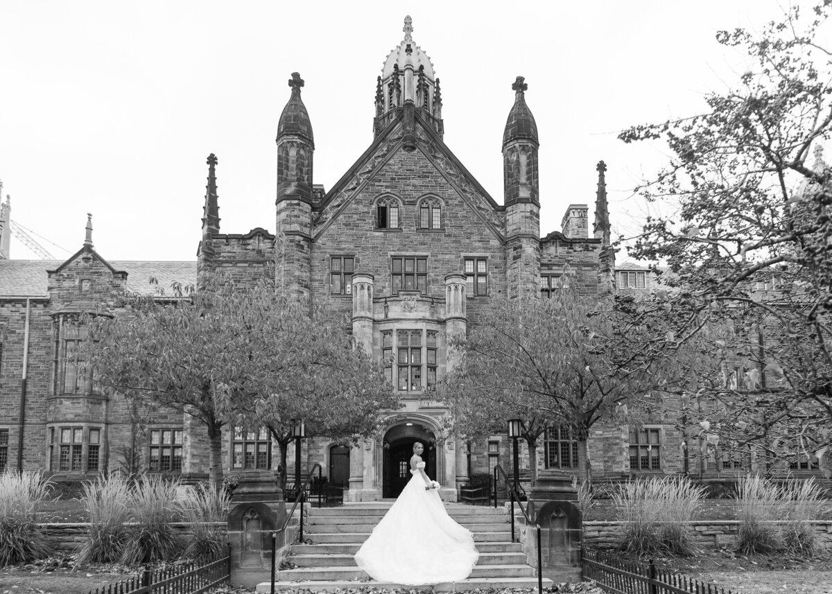 Iconic image of a bride on the steps of a castle with a long wedding gown in black and white