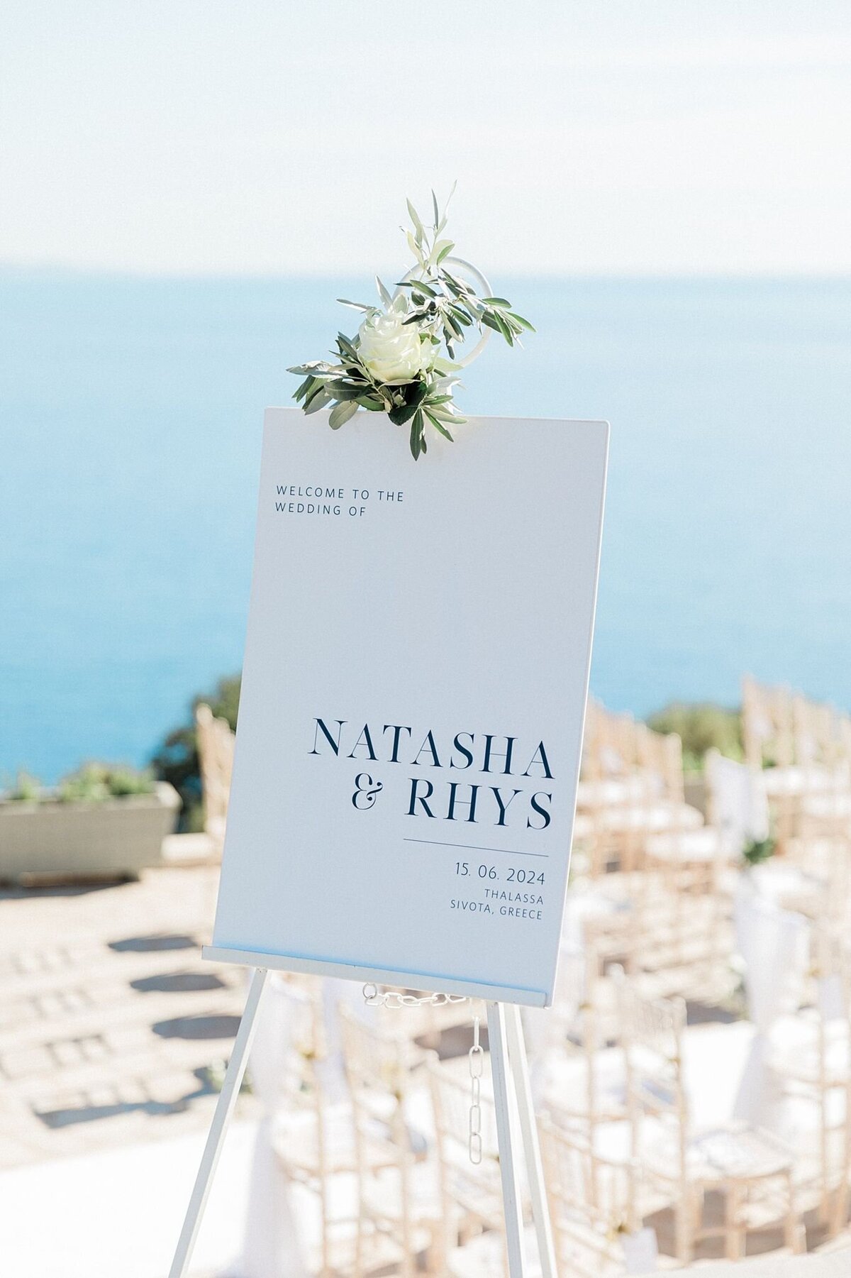 Minimalist white wedding welcome sign for Natasha and Rhys, with floral accent and ocean view