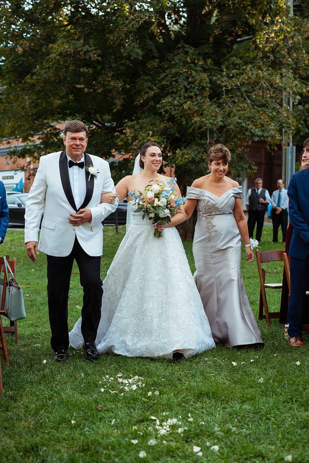 Bride walking down aisle with her parents hand in hand