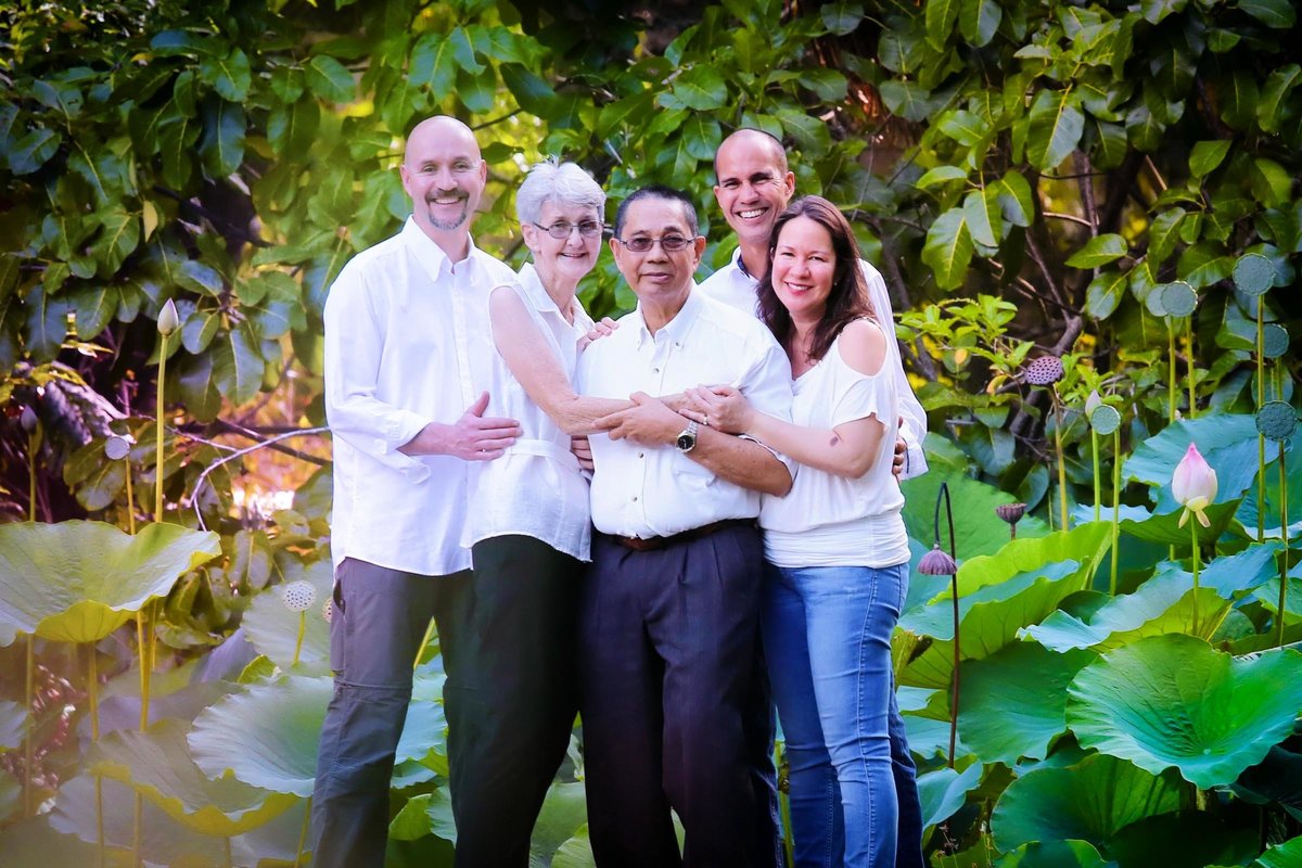 Adult family in group hug around mom and dad in nature. Photo by Ross Photography, Trinidad, W.I..