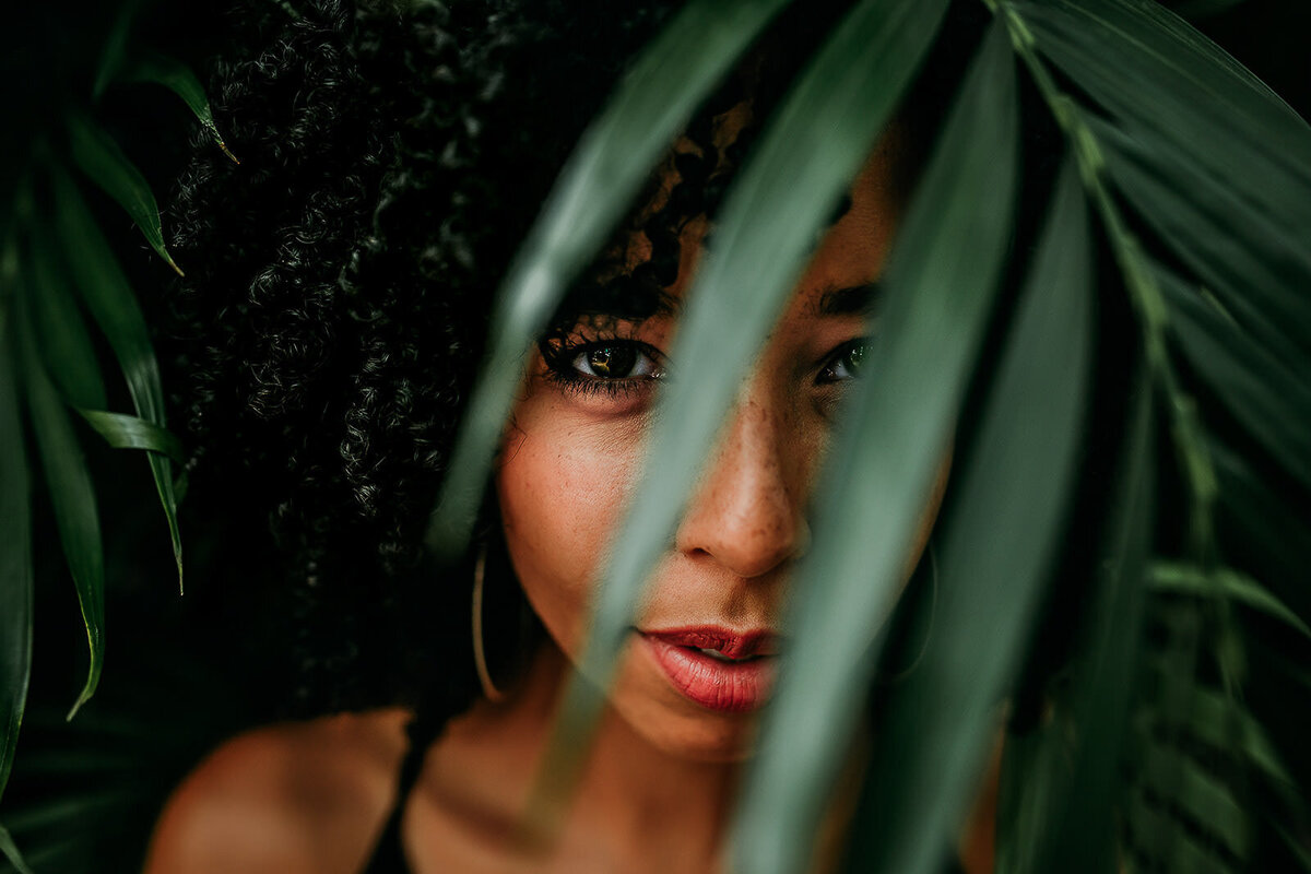 girl looking through palm branch