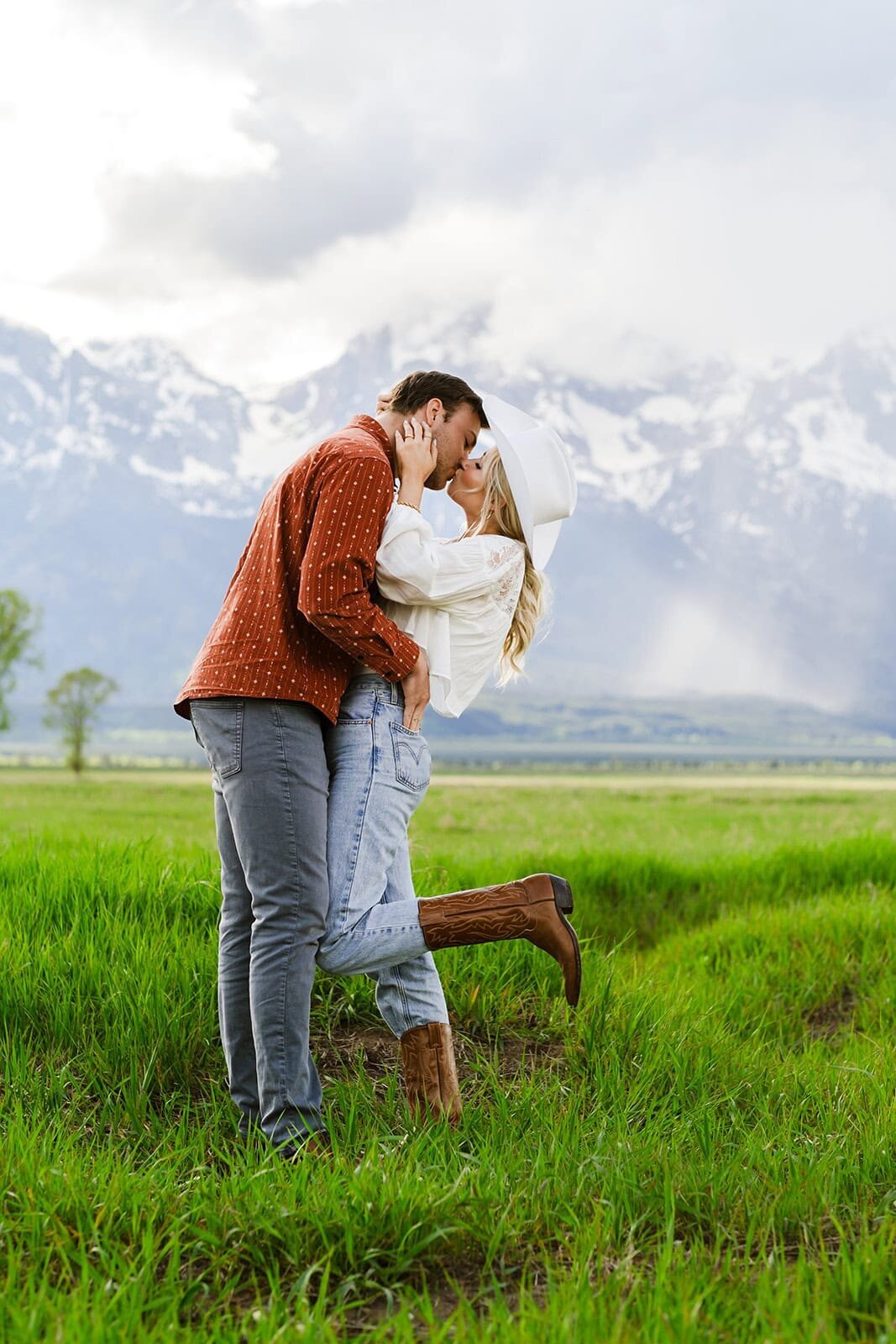 Spring engagement portraits in Jackson Hole. Couple kisses with Grand tetons in the background.