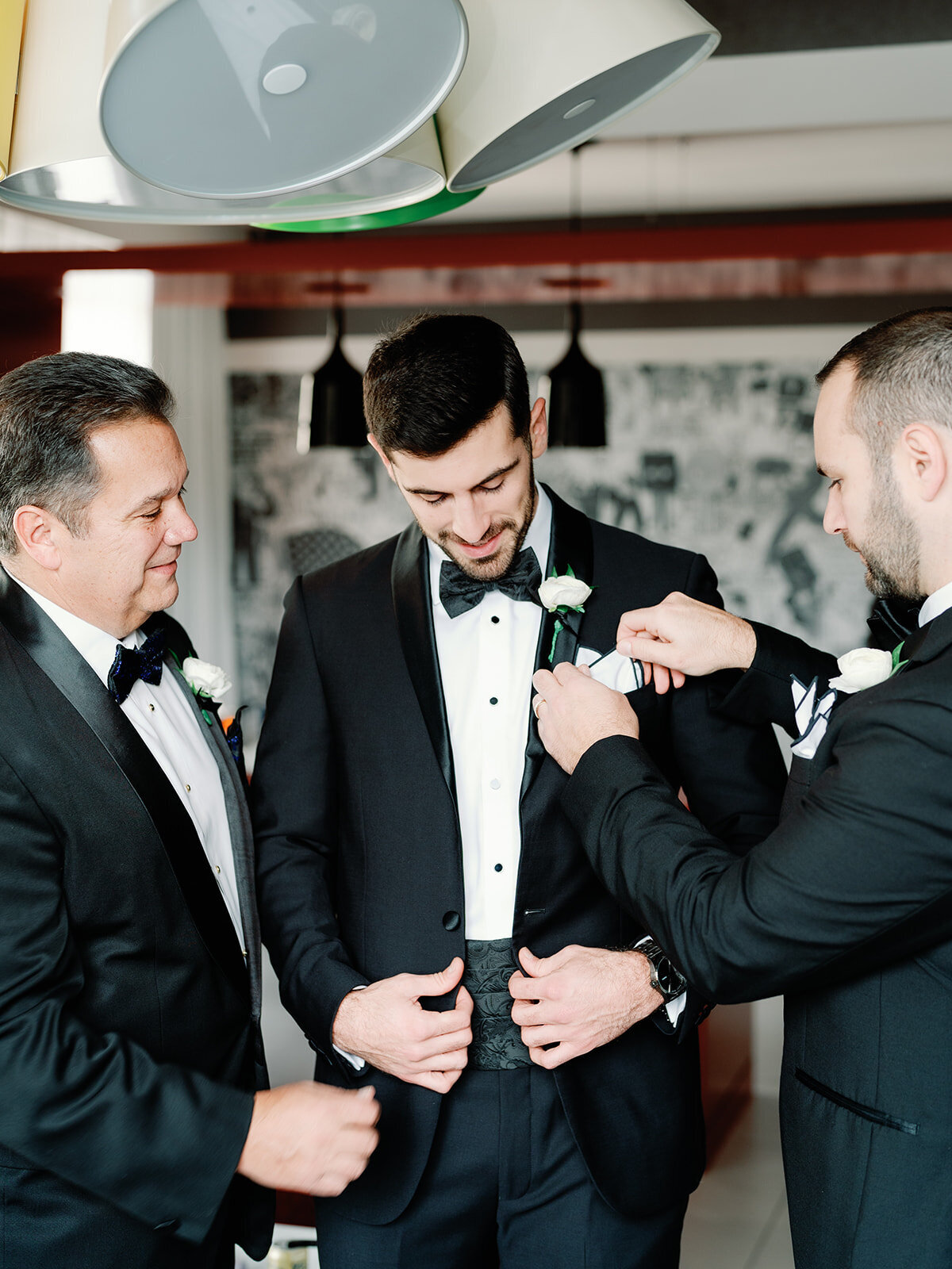 Best man and dad help groom get ready on wedding morning.