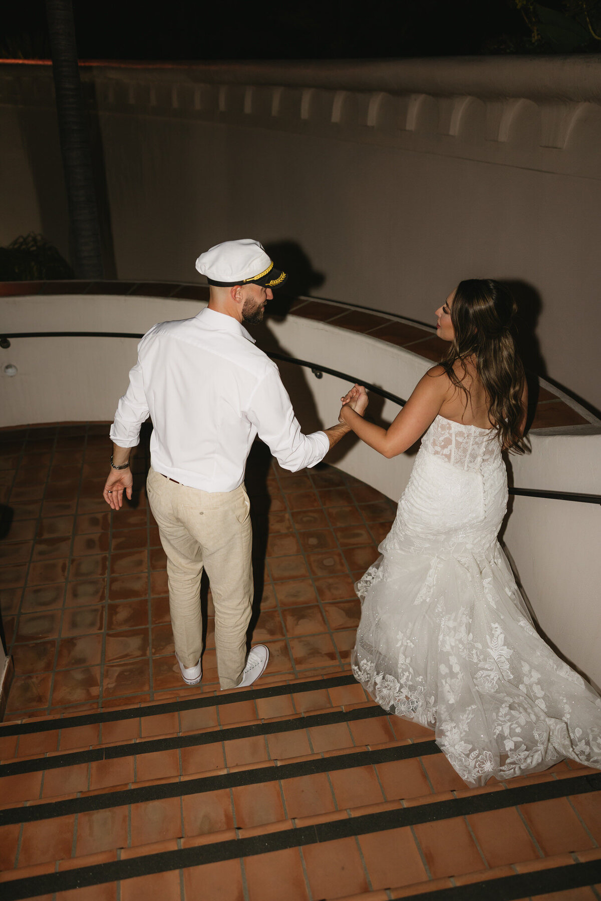 Bride and groom walking down stairs and holding hands at Hilton Beachfront Resort Santa Barbara