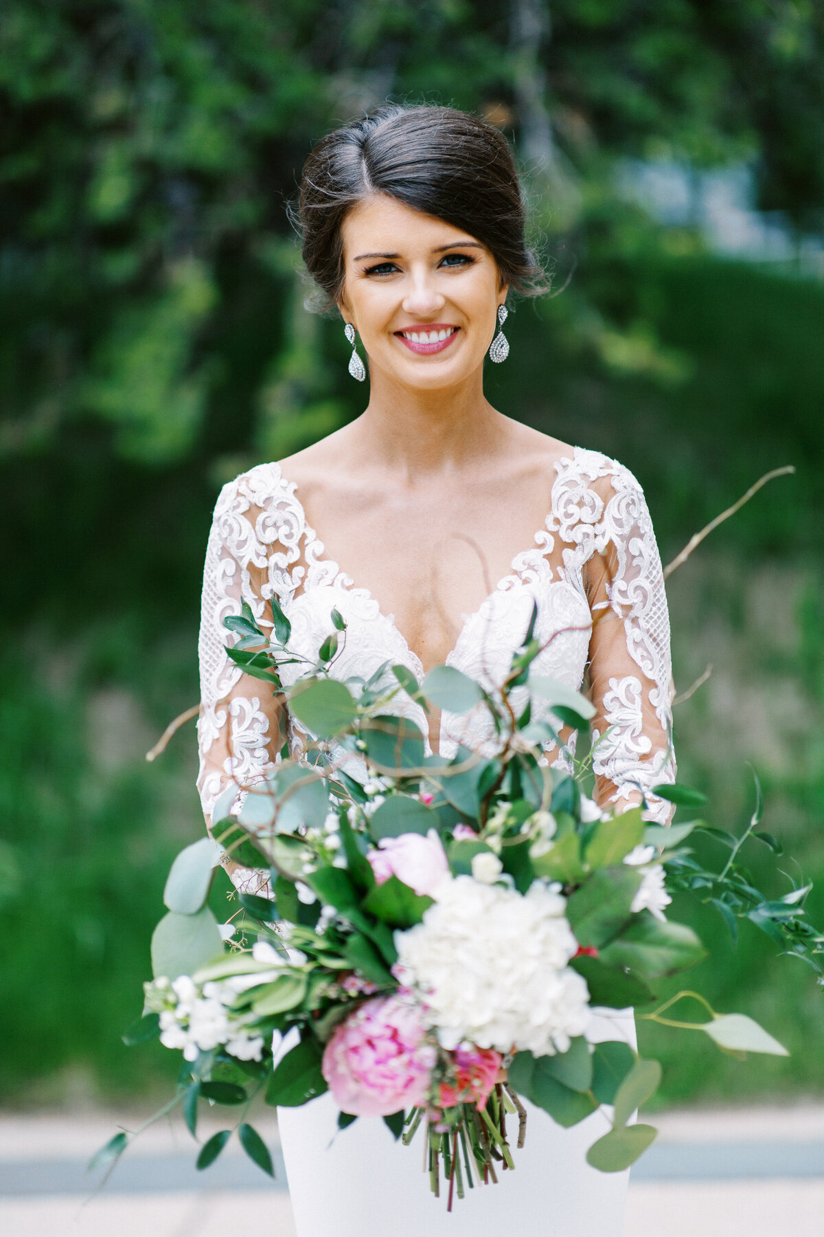 Minnesota bride smiling brightly on her wedding day in Minneapolis, holding her elegant bridal bouquet. Captured by Toly Dzyuba Photography.